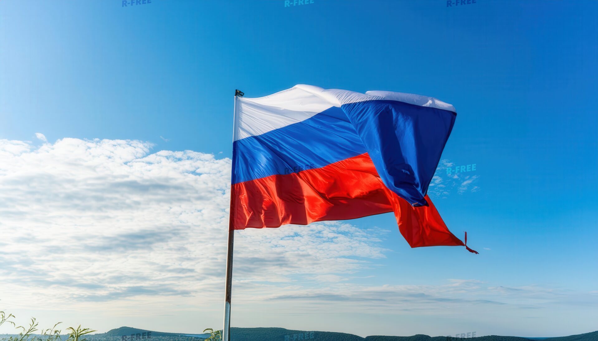 山影と薄雲を望む青空で風になびくロシア国旗