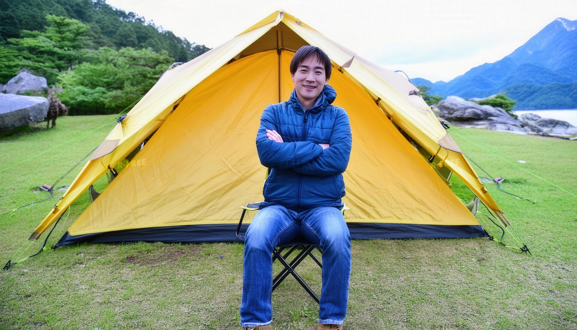 キャンプ場で黄色いテントの前に座る男性・腕を組んで微笑む