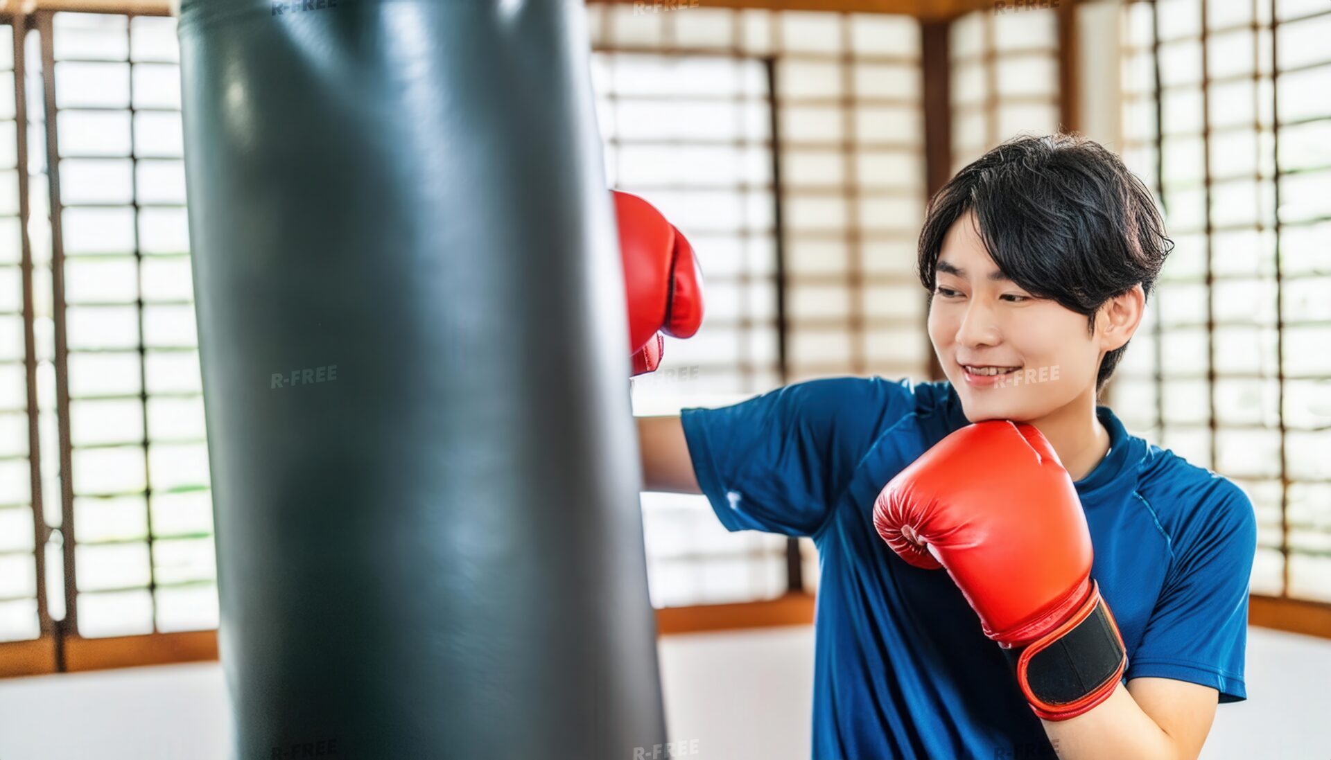 サンドバッグに向かい構える赤いグローブを着けた男性