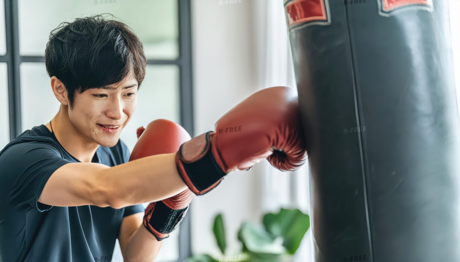 ボクシンググローブでサンドバッグを叩く男性