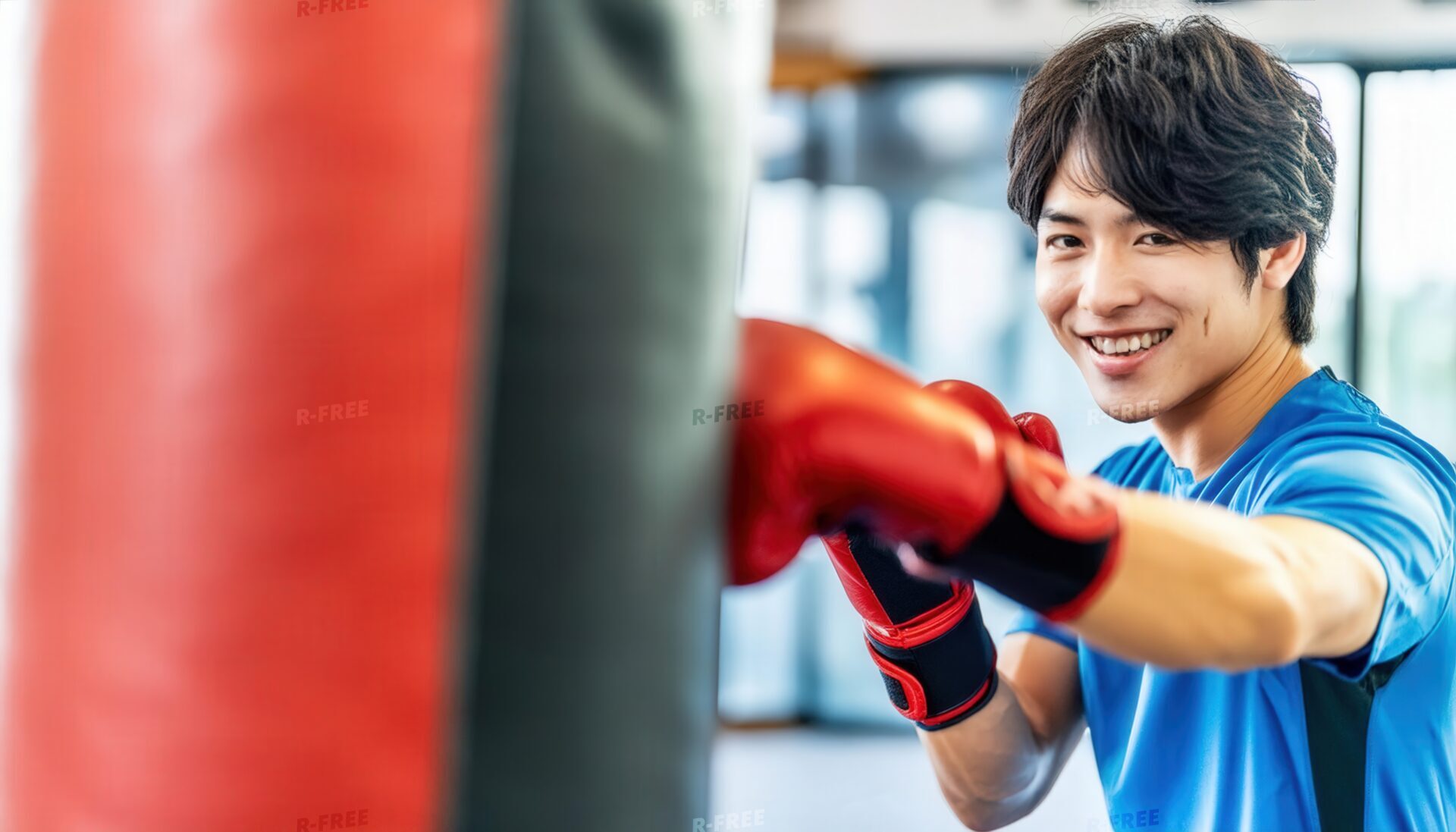 サンドバッグをパンチする笑顔の男性