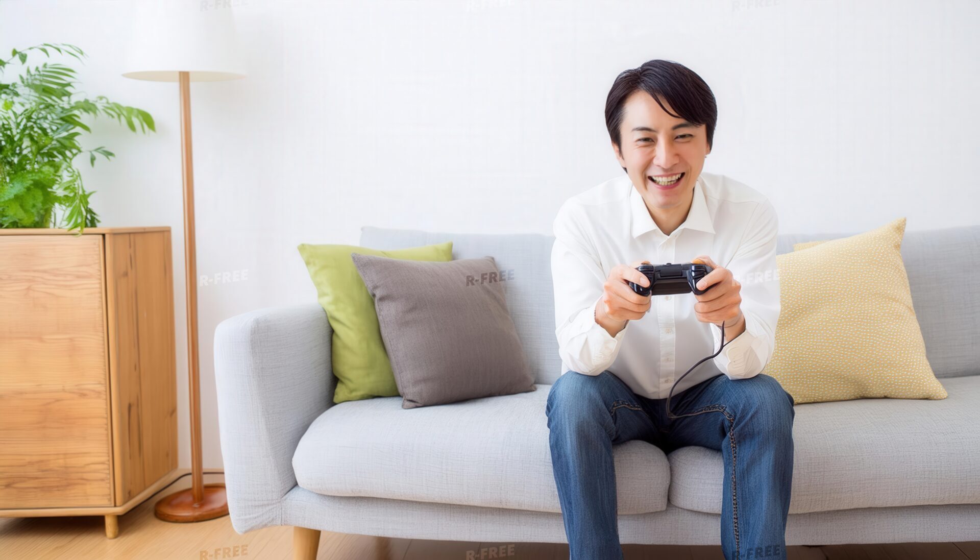 カメラに笑顔を向ける白シャツ姿の30代男性がゲーム