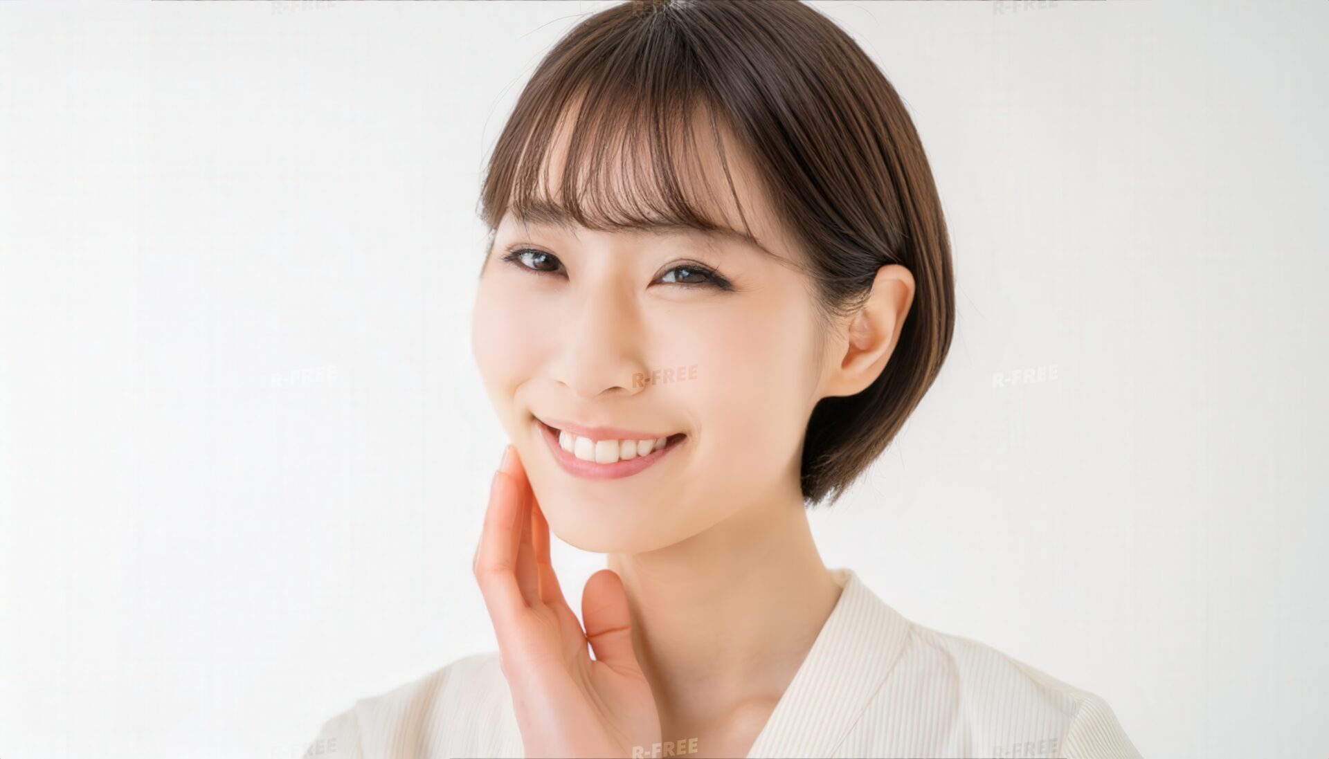 頬に手を添えて歯を見せて微笑む白い服の笑顔の女性