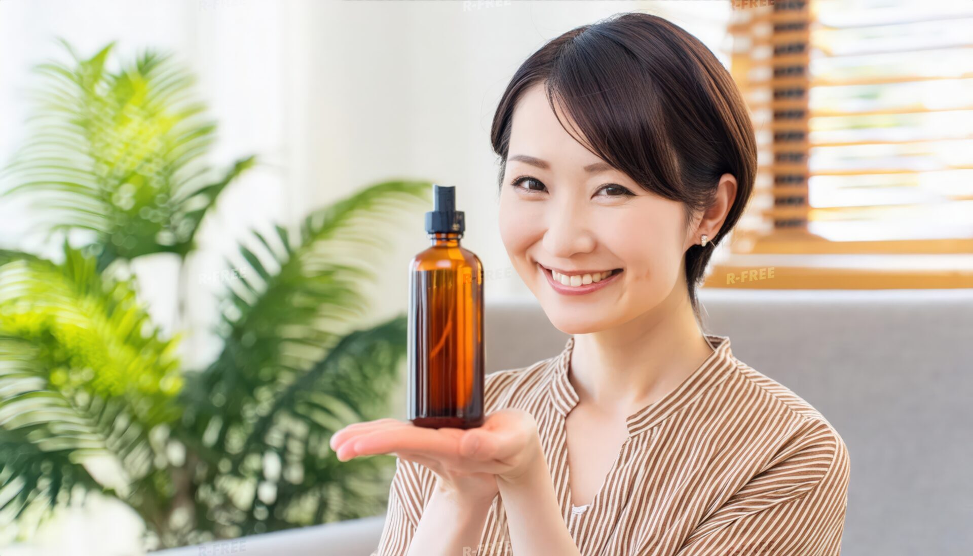 化粧水・美容液のボトルを手に微笑むストライプブラウスの女性