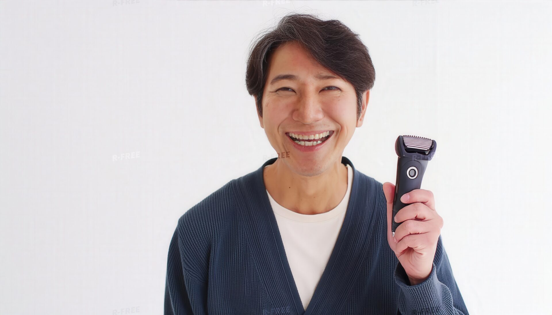シェーバーを持つ男性・紺色カーディガンで満面の笑顔の正面姿