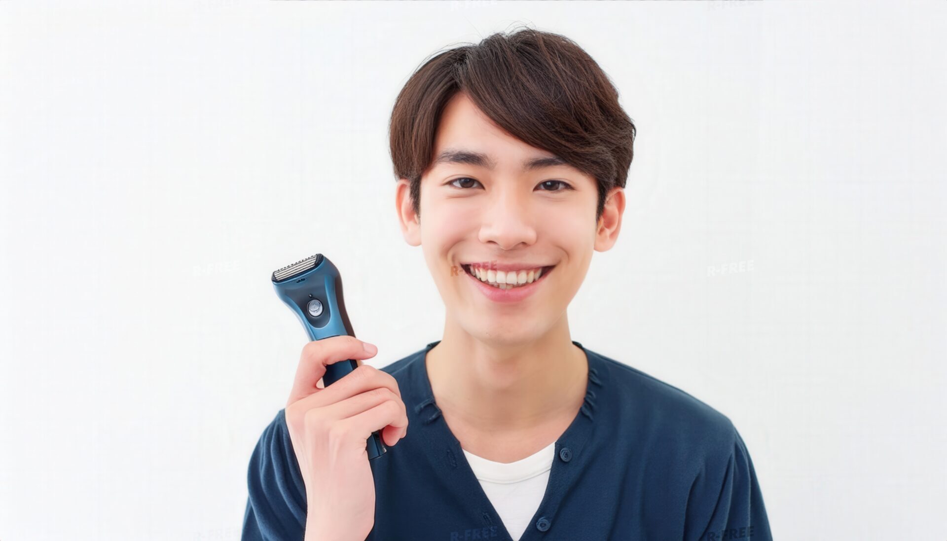 電気シェーバーを手に爽やかに微笑む紺色の服の男性