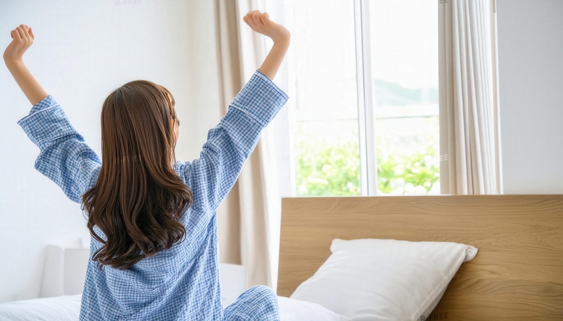 早起きして青いチェック柄パジャマで背伸びする女性