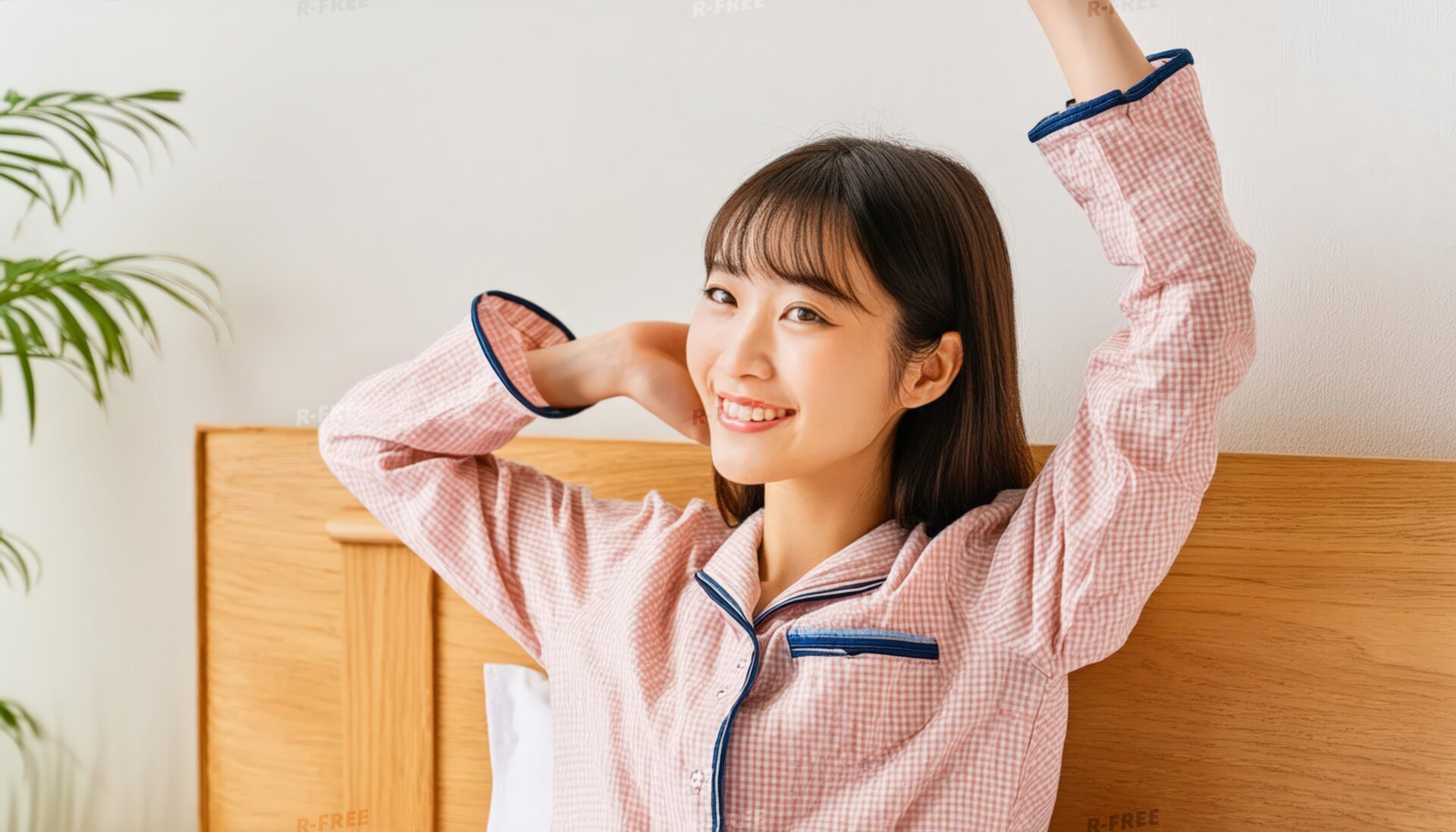 早起きして笑顔で腕を上げるピンクチェックの女性