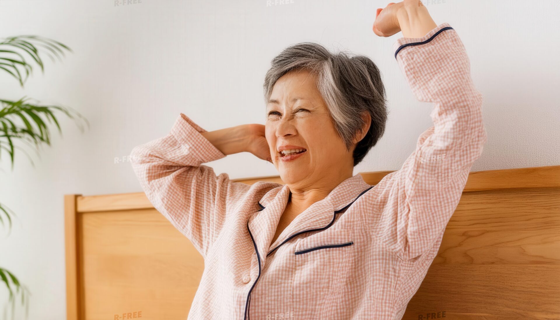 早起きして笑顔で両腕を伸ばす白髪のシニア女性