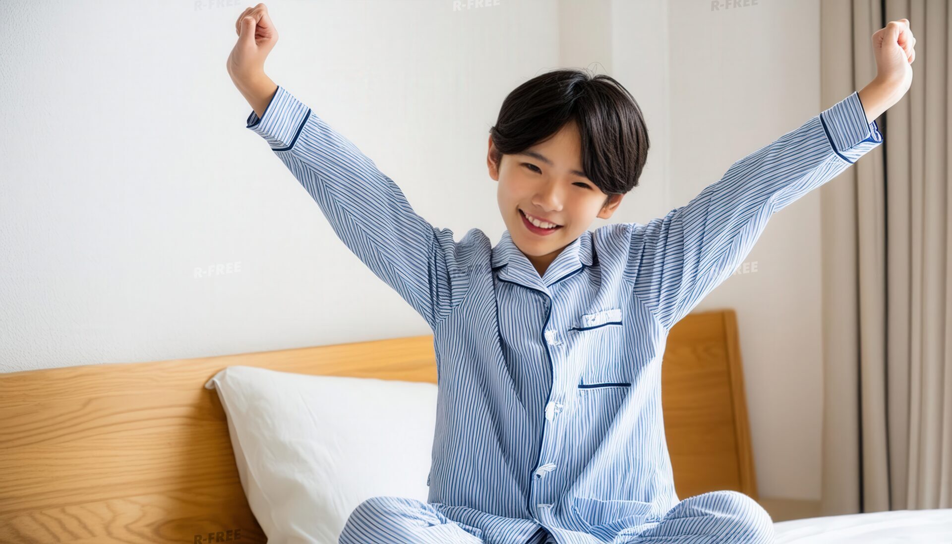 朝早起きしている笑顔の少年と木製ヘッドボードの寝室