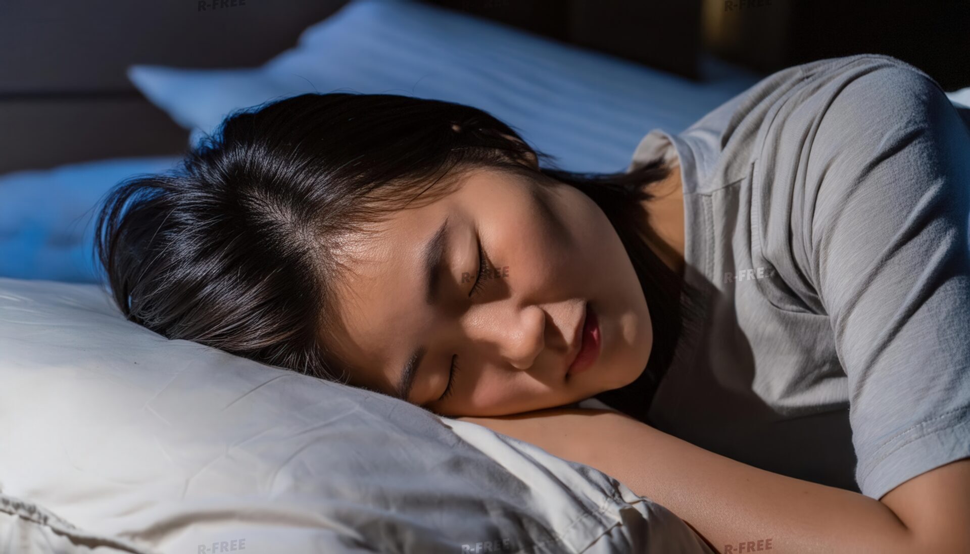 夜に就寝する灰色Tシャツの若い女性