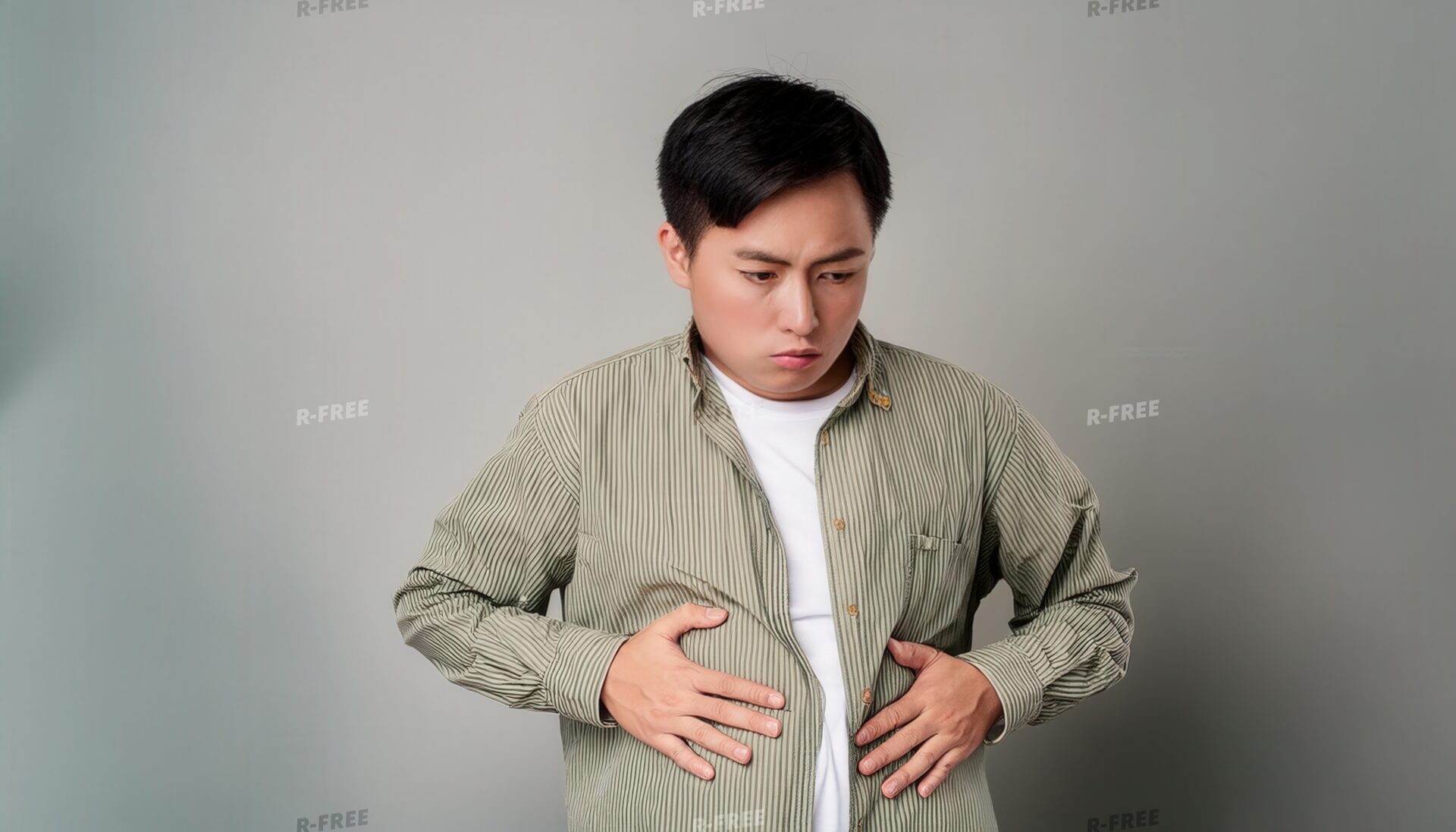 グレー背景でお腹を押さえる男性