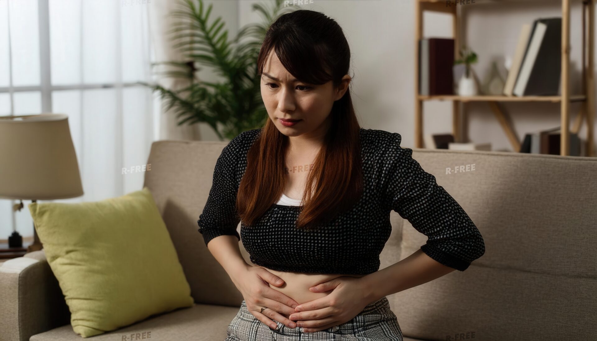 暗い部屋でお腹を押さえる女性