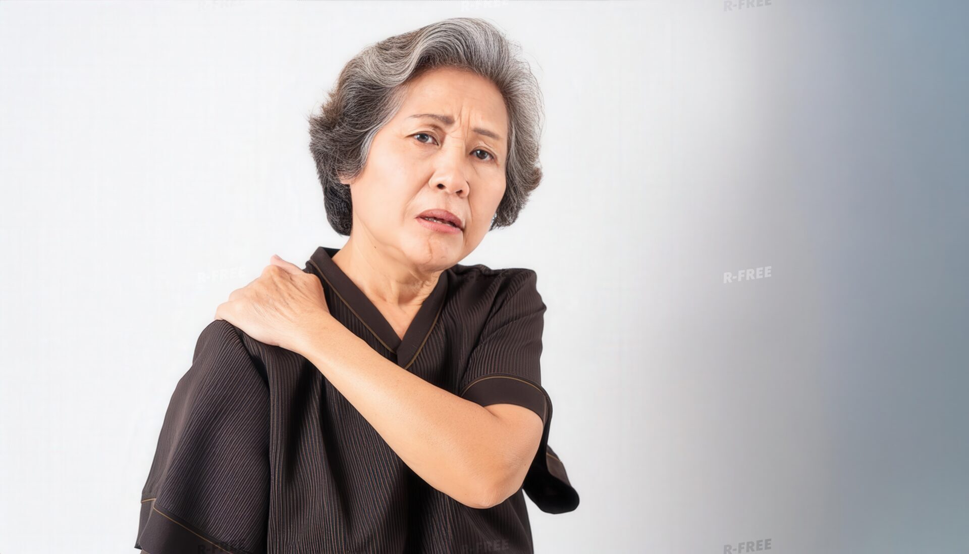 肩こりで右肩を揉む苦悶の表情のシニア女性