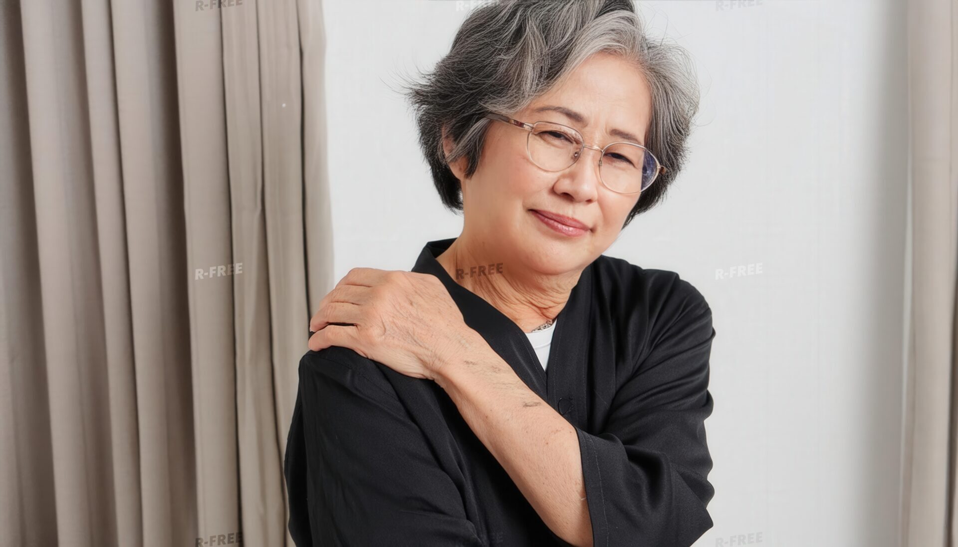 肩こりで肩に手を置く眼鏡姿のシニア女性