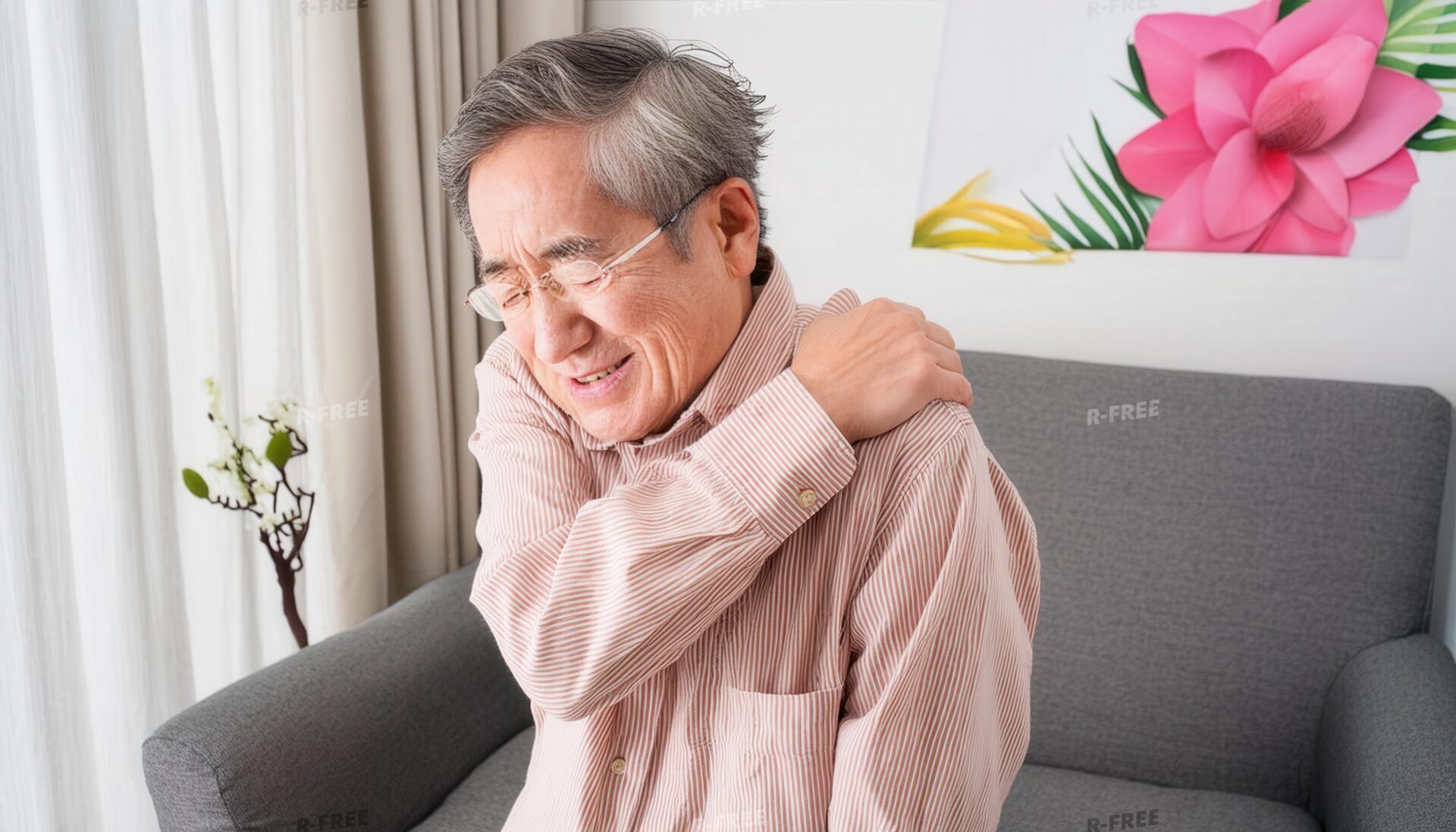 肩こりで左肩を押さえる花の絵を背景にしたシニア男性