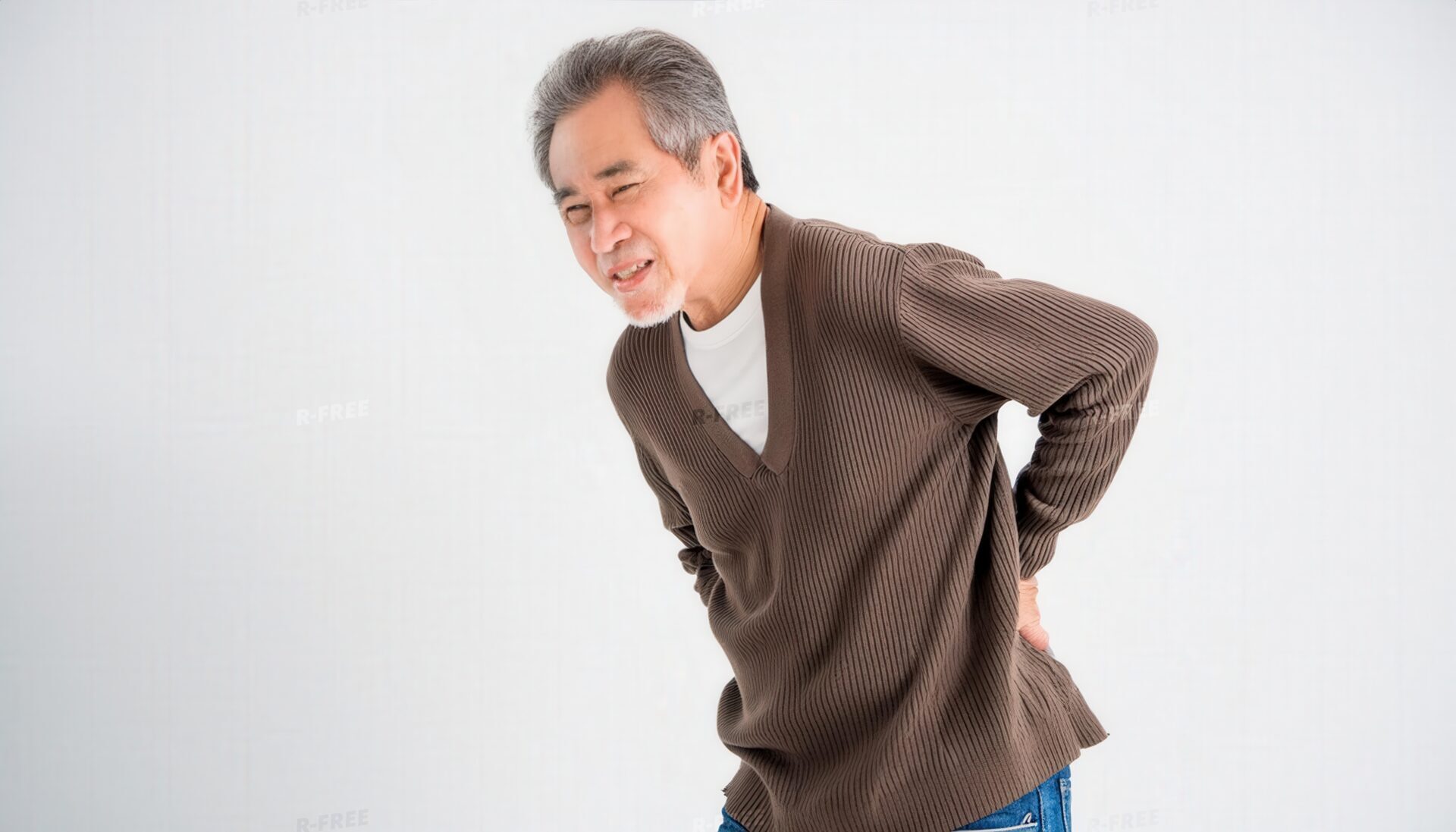 前かがみで両手で腰を押さえる白髪混じりの男性