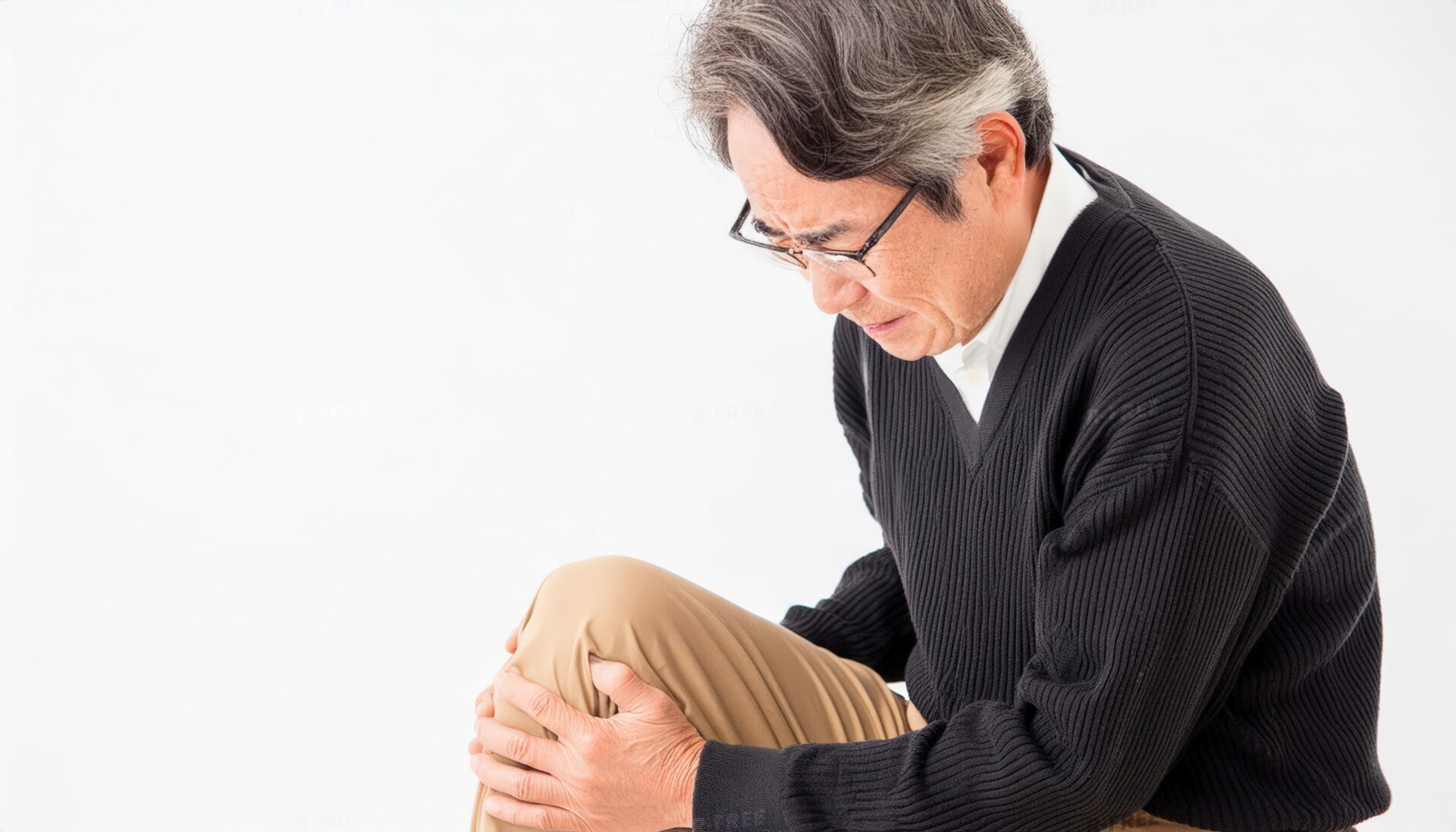 膝を抱える高齢男性