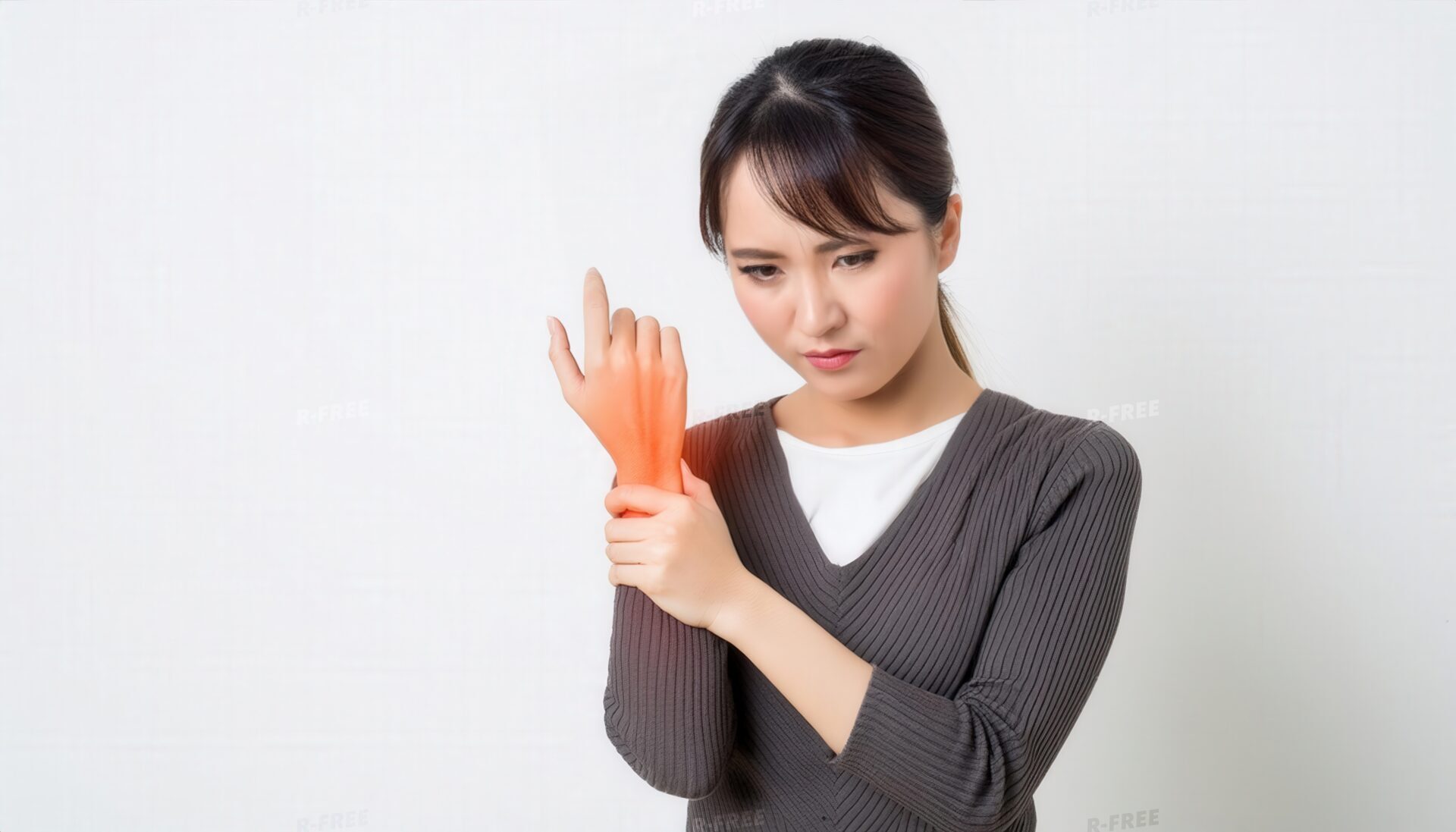 グレーニットで赤いエフェクトの左手首を押さえる女性