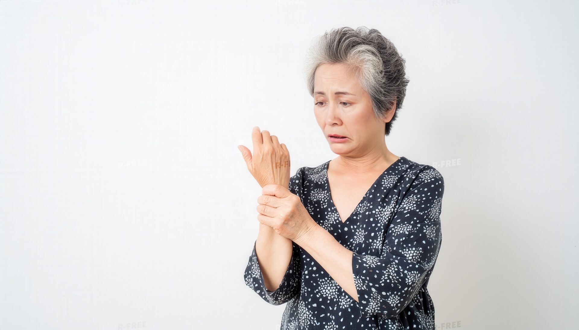 紺色の柄物の服で手首を押さえる辛そうなおばあさん
