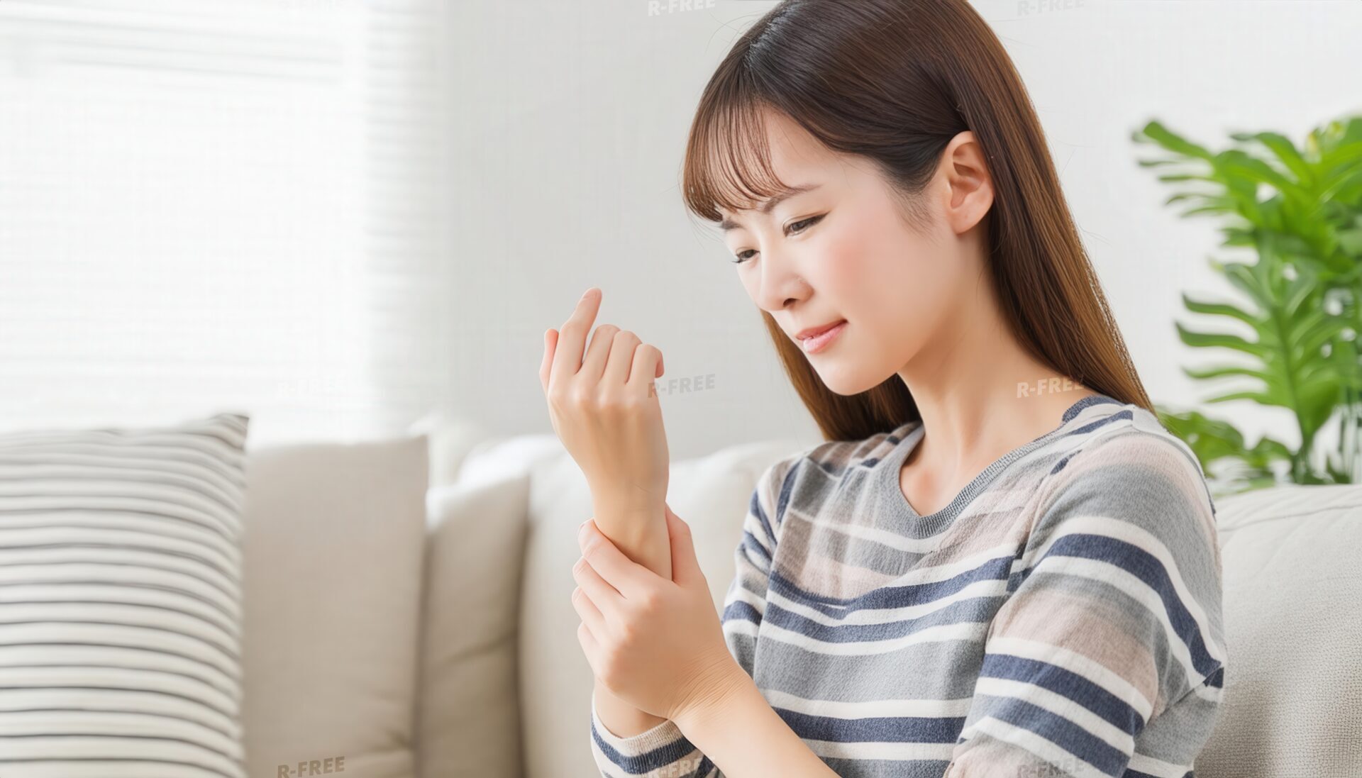ボーダー柄の服で左手首を押さえる自然光の女性