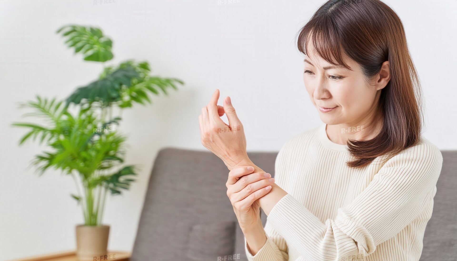 ベージュニットで手首を押さえ伏し目がちな女性