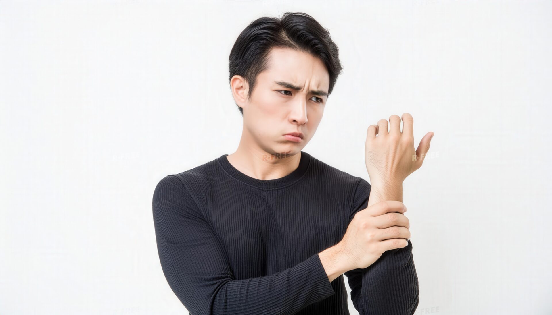 険しい表情で左手首を押さえる黒服の男性