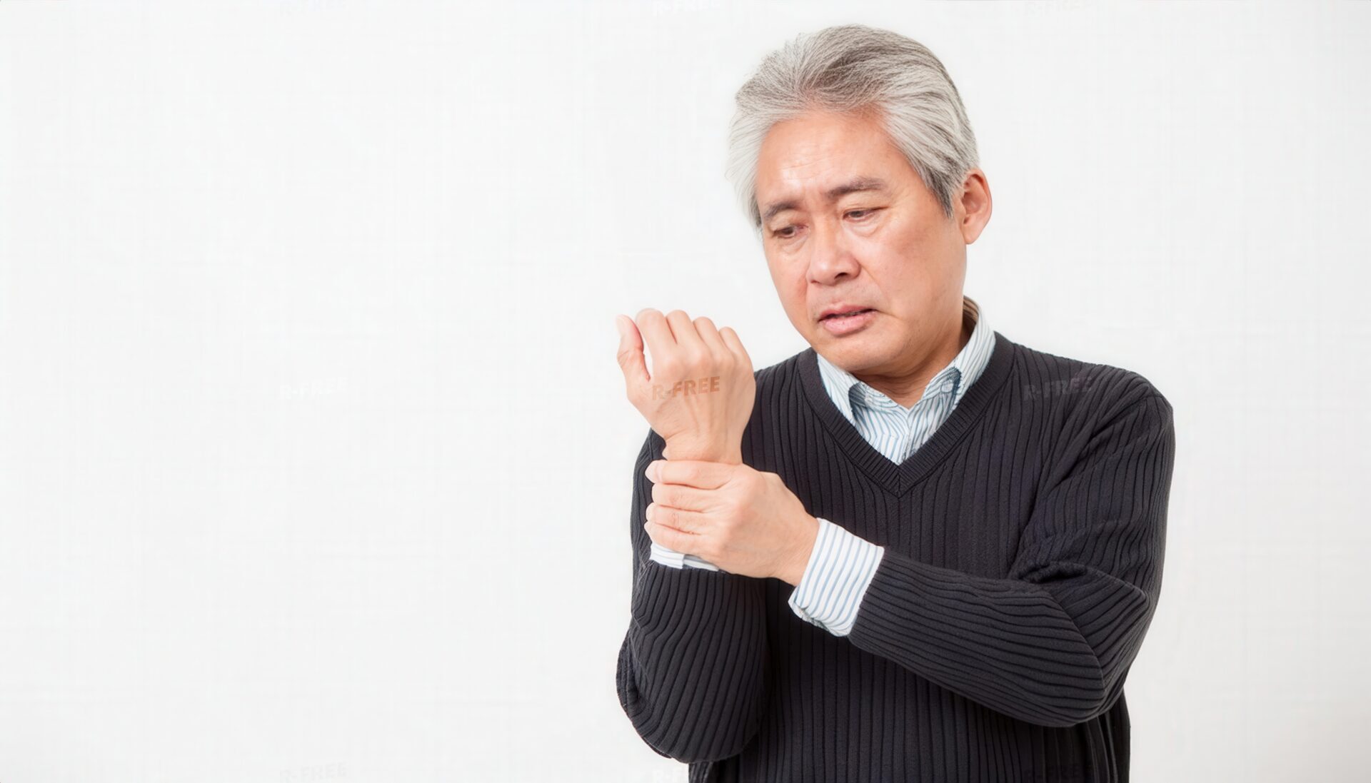 黒いVネック姿で左手首を押さえるシニア男性