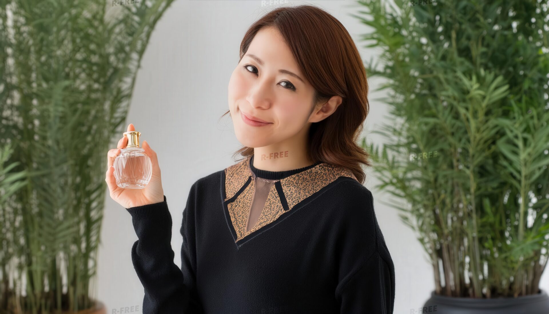 観葉植物に囲まれ香水を持つ30代女性の笑顔