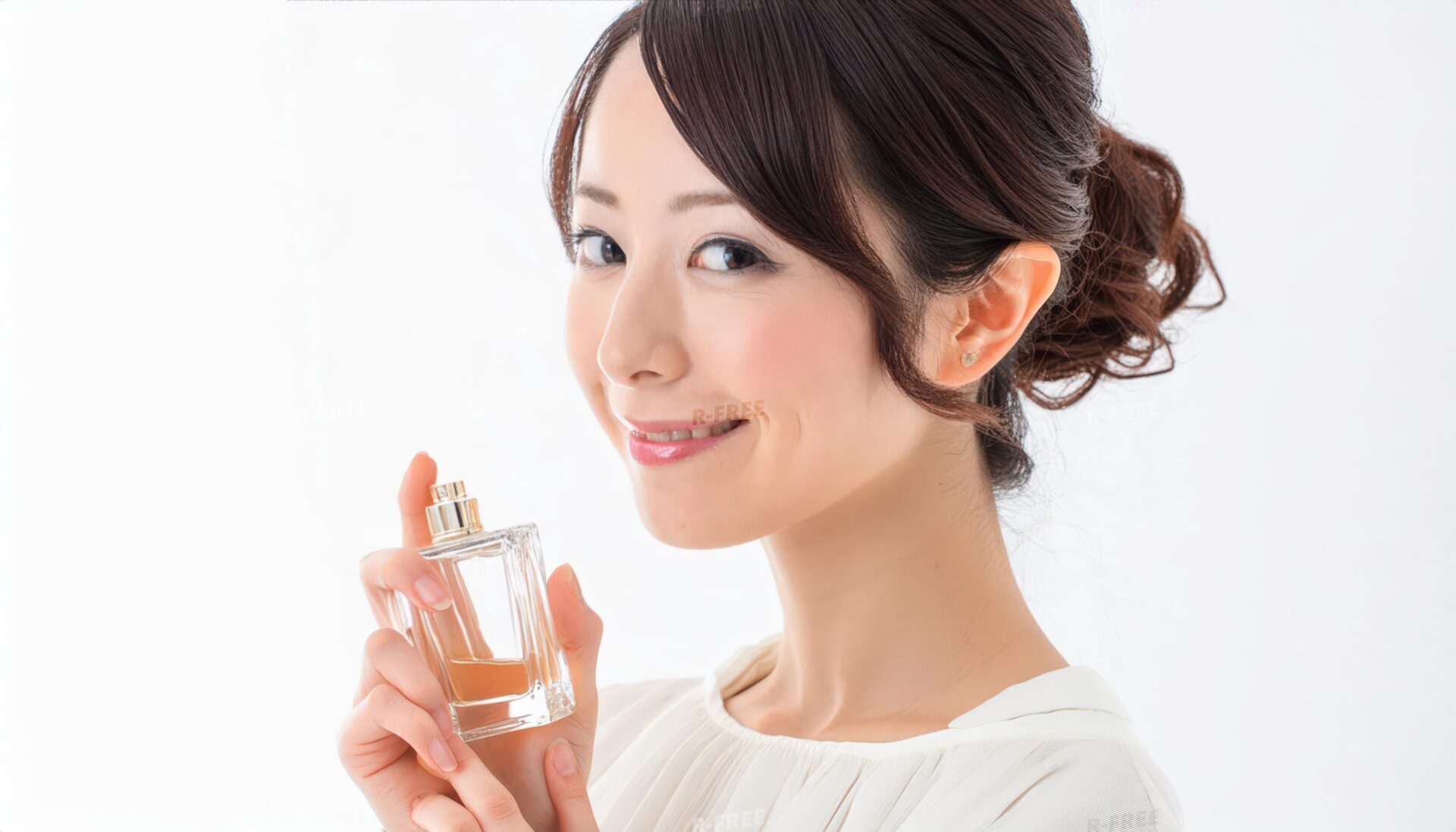 白ブラウスの30代女性が琥珀色の香水を手に笑顔