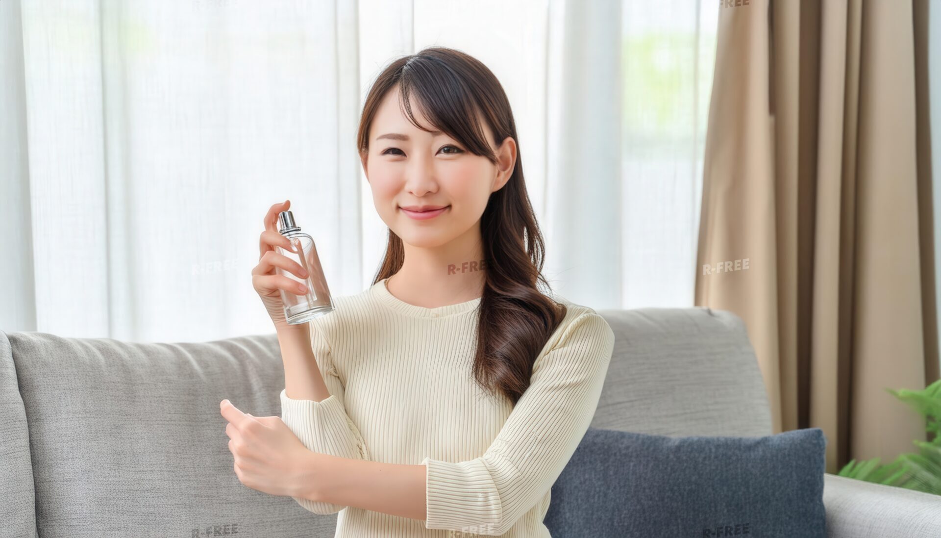 ベージュニット女性が香水を腕に吹きかける