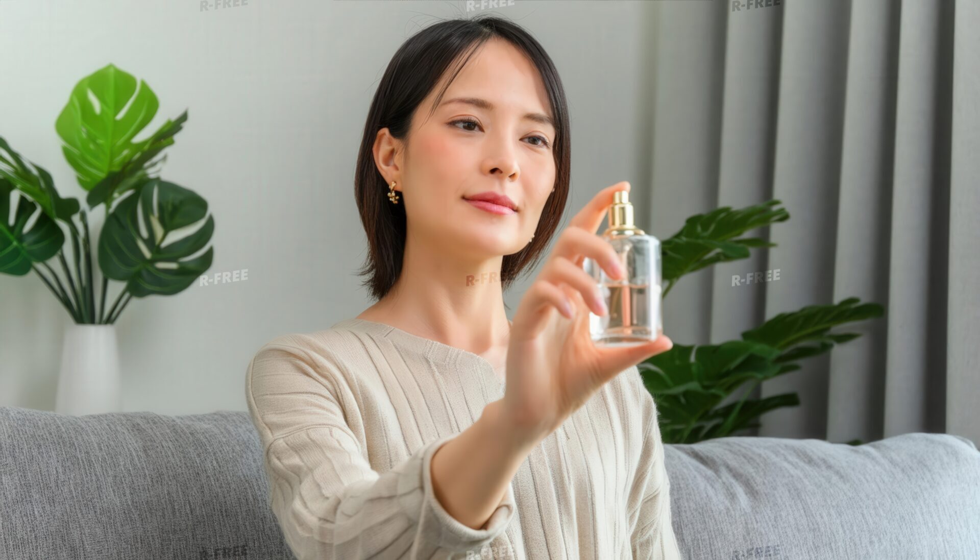 モンステラを背景に香水を見つめる女性