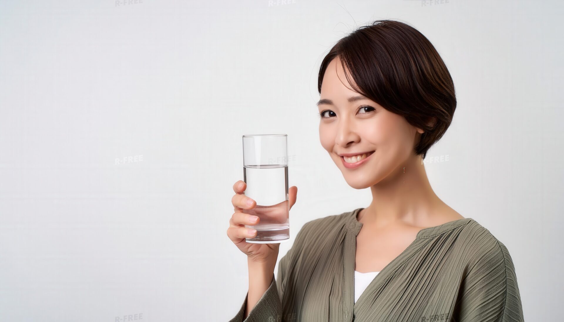 グラスの水を手に持ち微笑む人