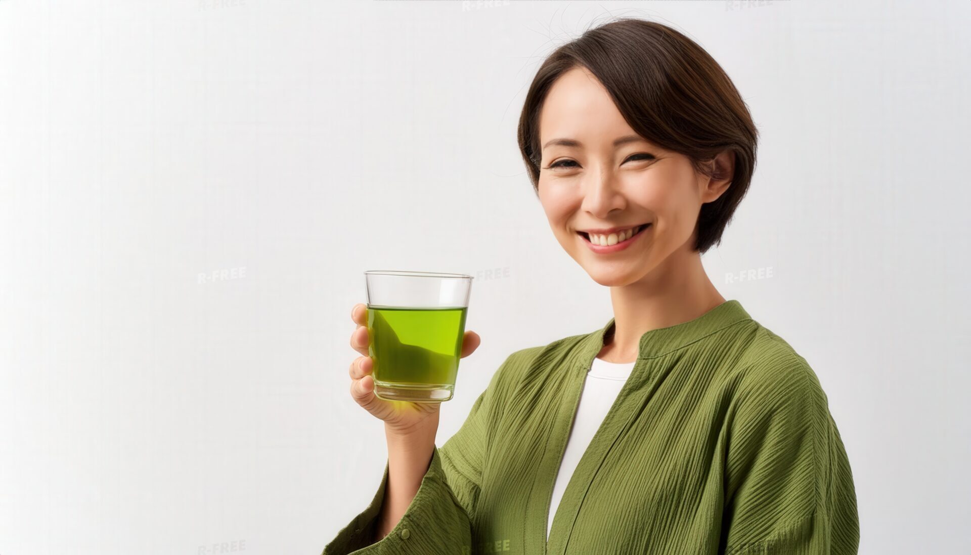 緑茶入りグラスを持って笑う緑色の上着の女性