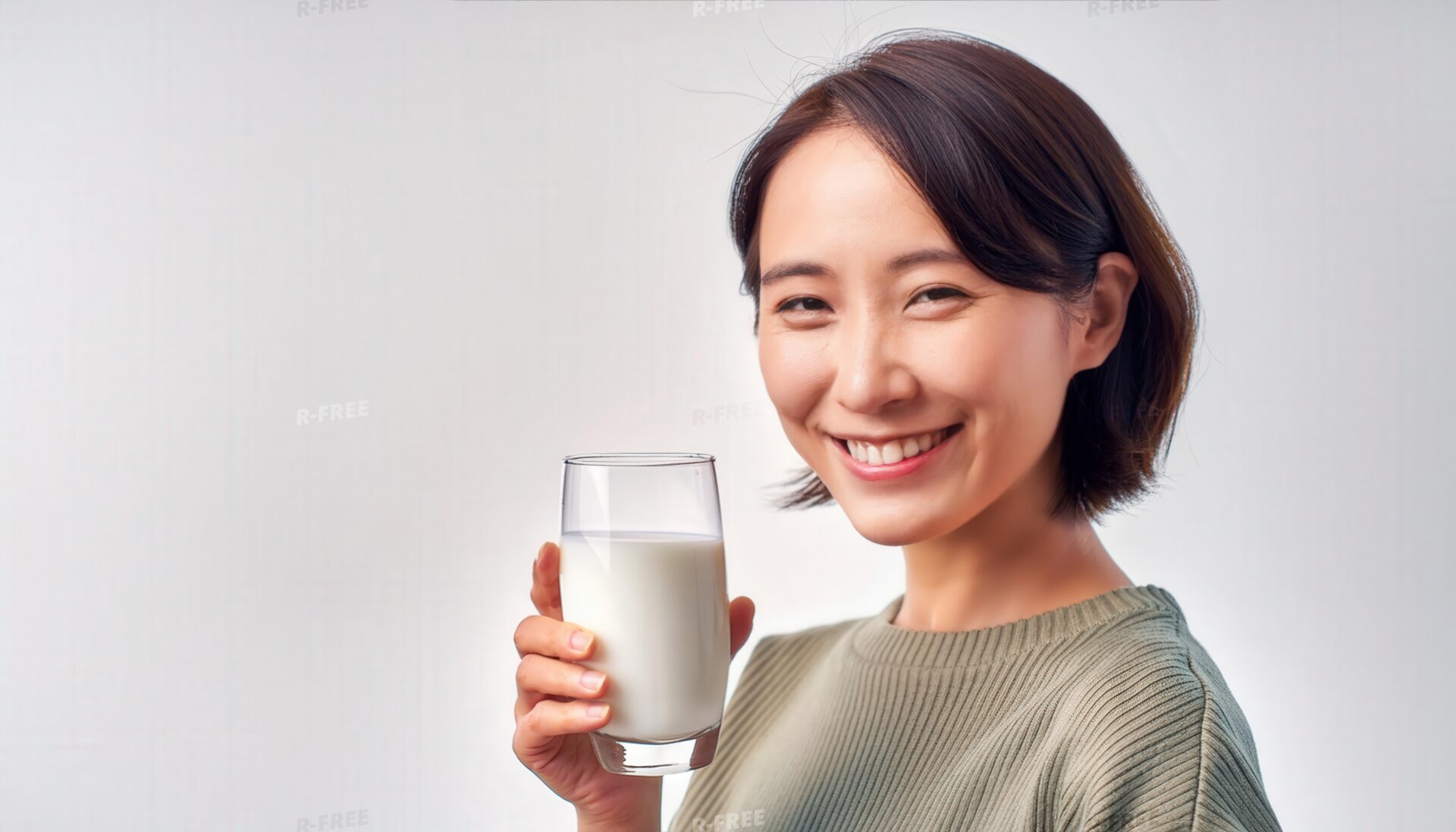 淡いグリーンのニットで牛乳を持つ笑顔の女性