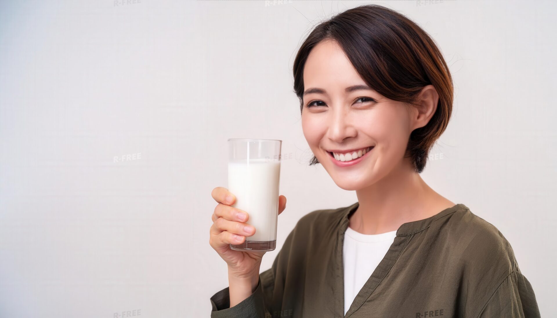 カーキ色の長袖服で牛乳を掲げる笑顔の女性