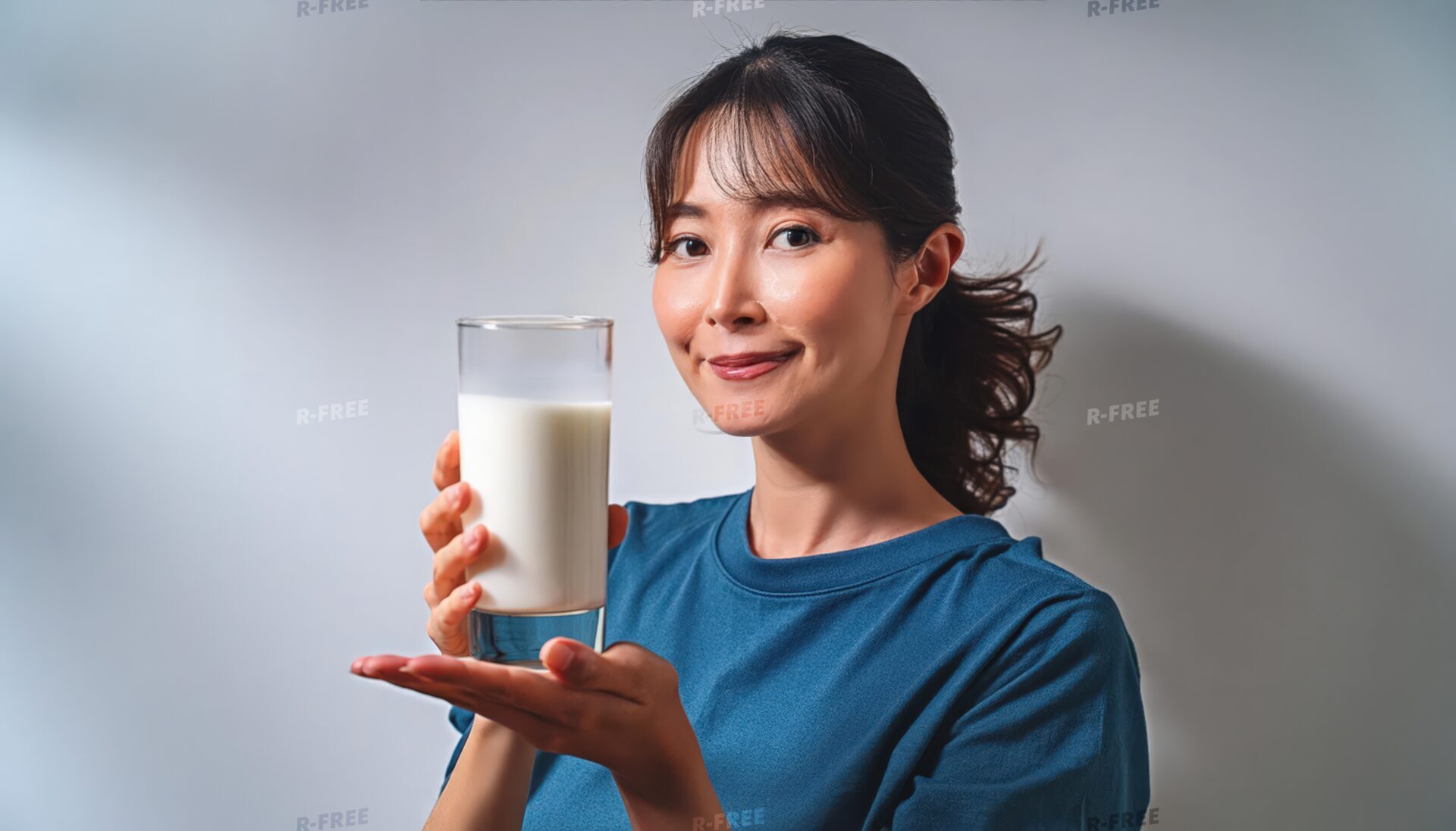 青いTシャツで牛乳を両手で持つ笑顔の女性