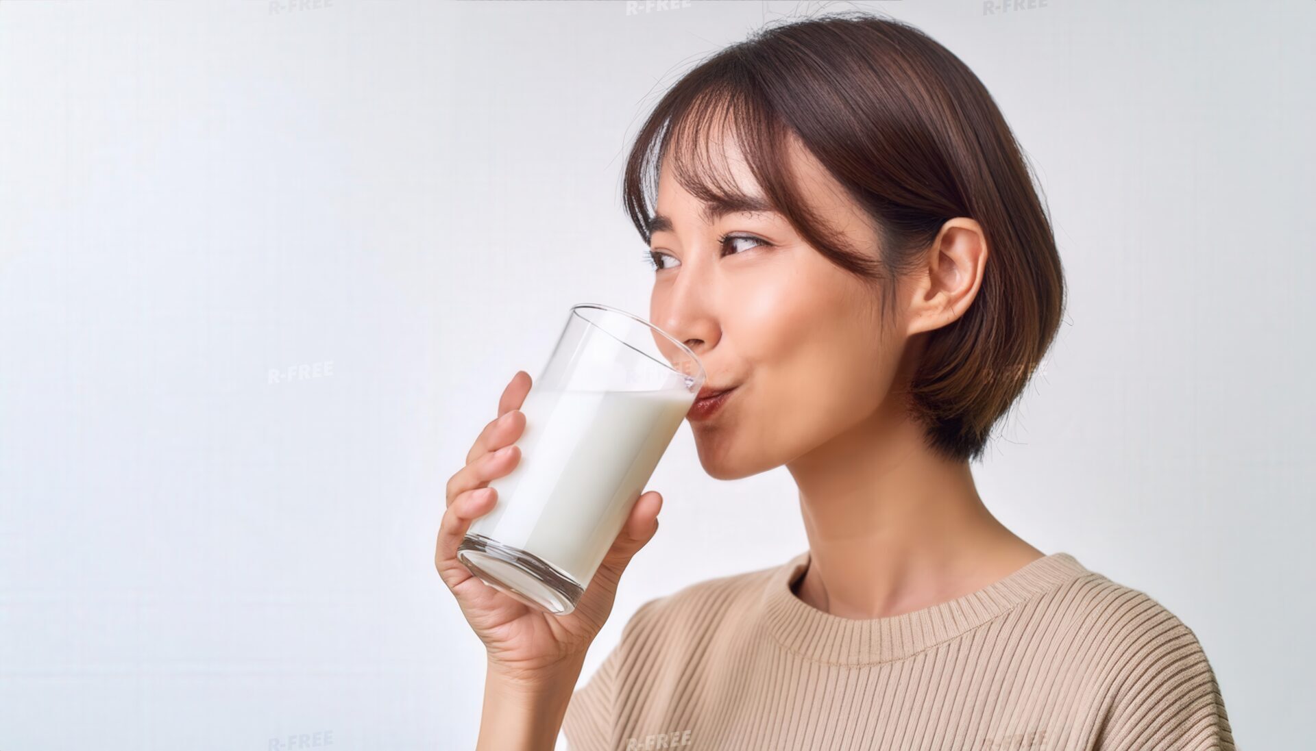 ベージュのニットで牛乳を飲む茶髪の女性