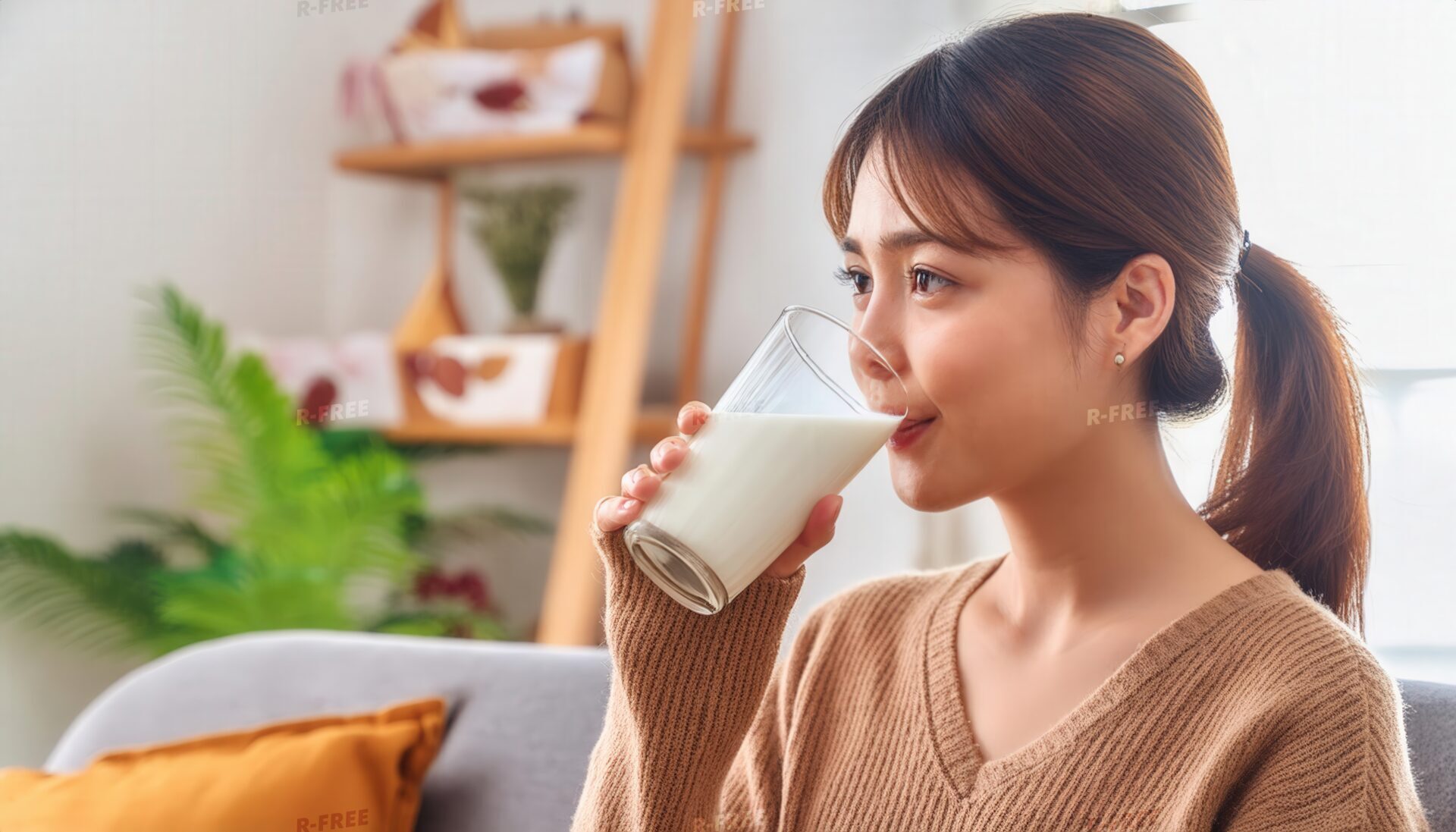 室内で牛乳を飲む若い女性（横向き）
