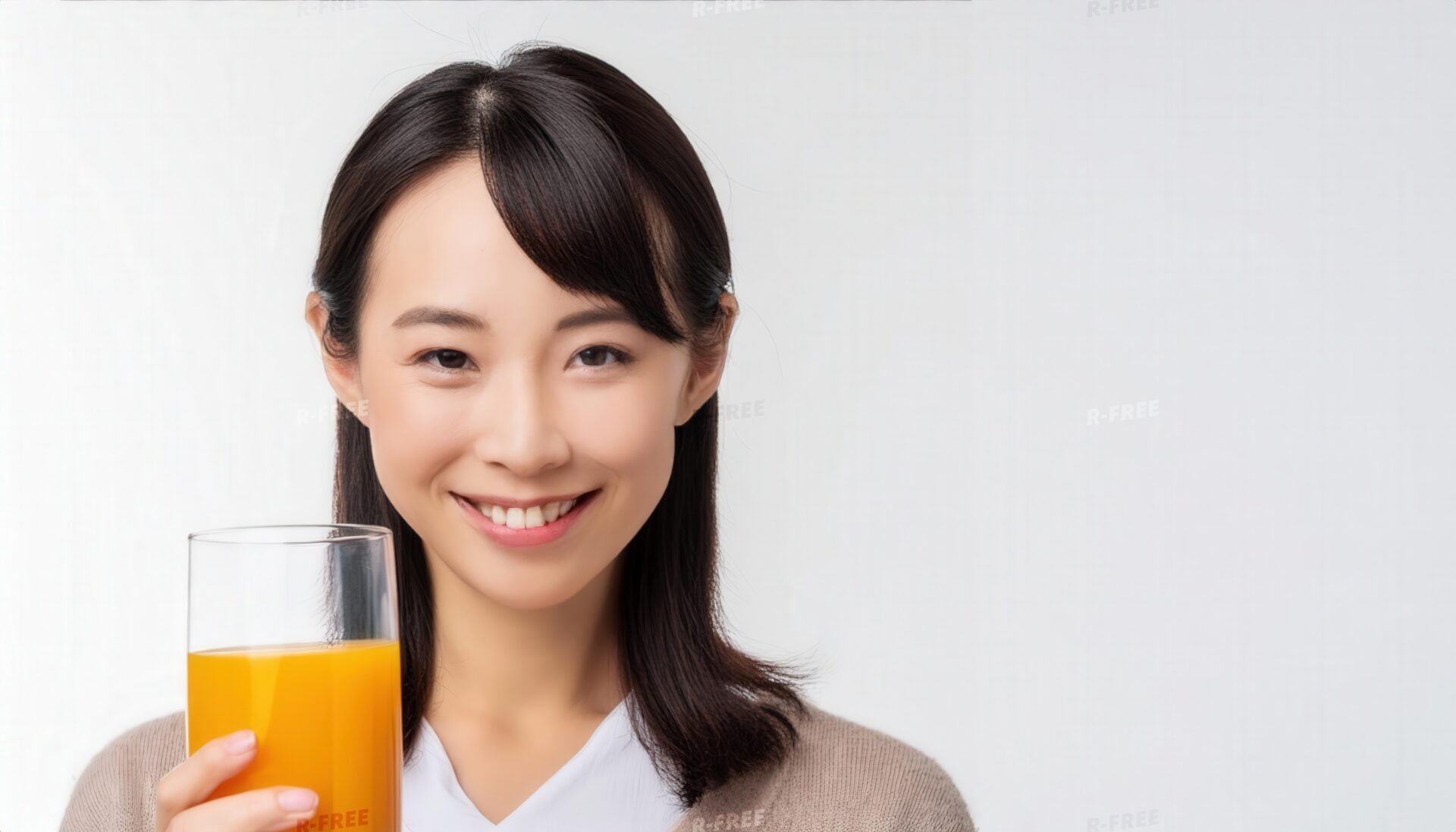 笑顔でオレンジジュースを持つ長い黒髪の若い女性