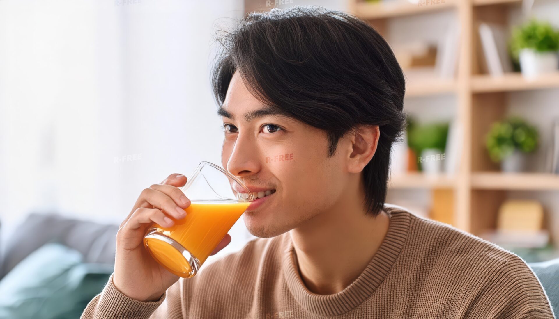 自宅でオレンジジュースを飲む笑顔の男性