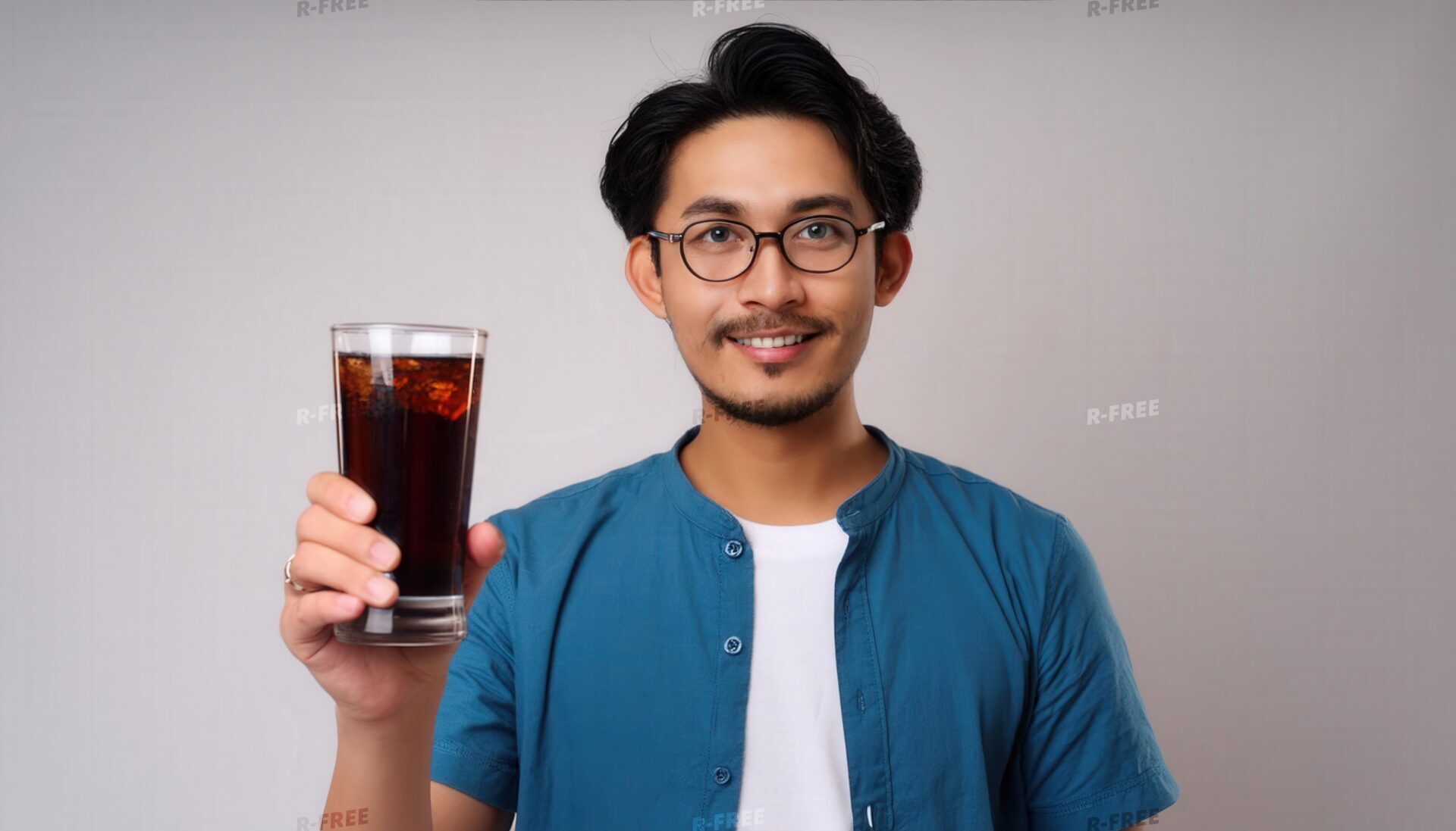 白背景で黒い炭酸飲料のグラスを差し出すメガネの若い男性