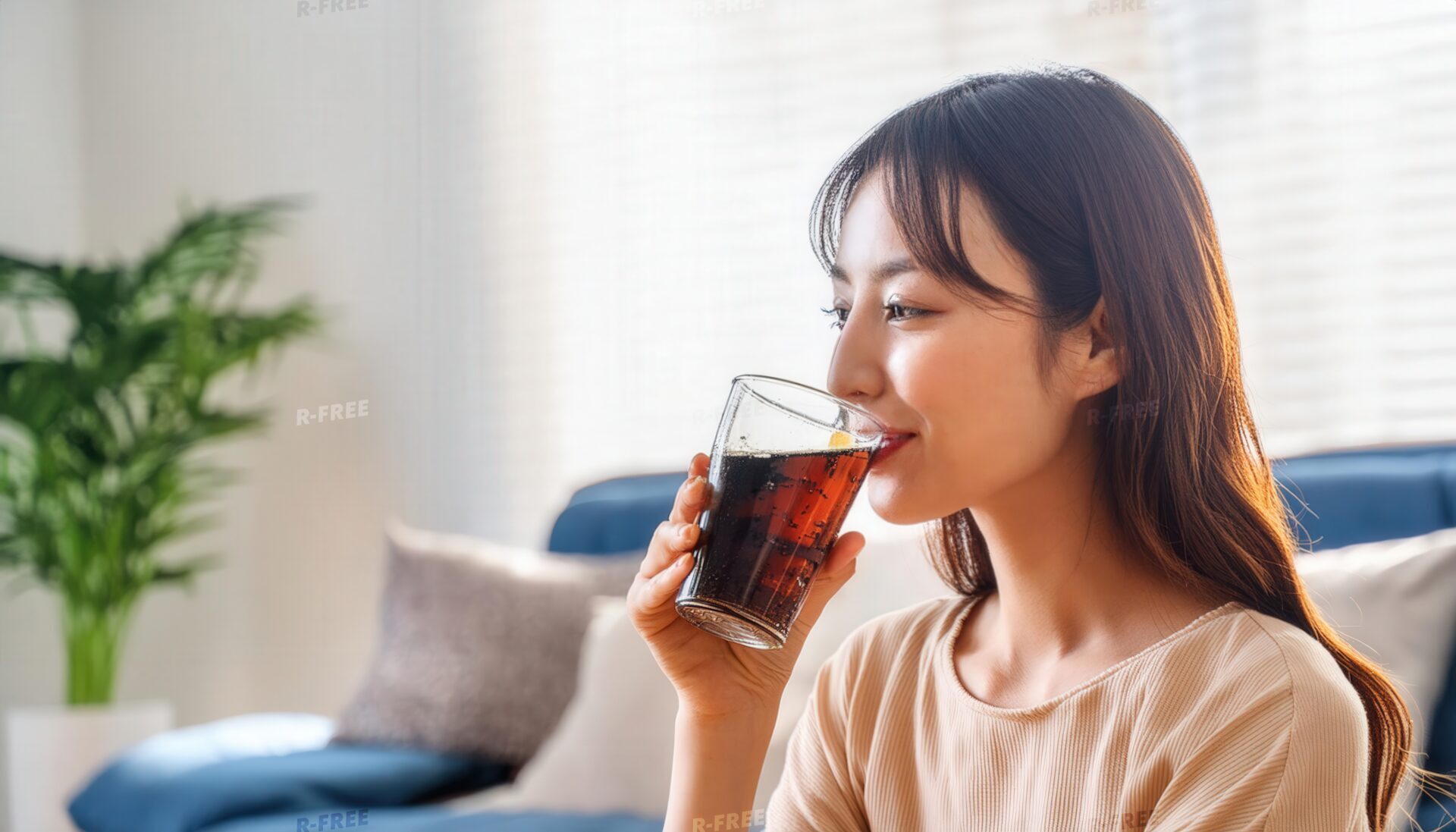 室内で黒い炭酸飲料を飲む長い黒髪の人