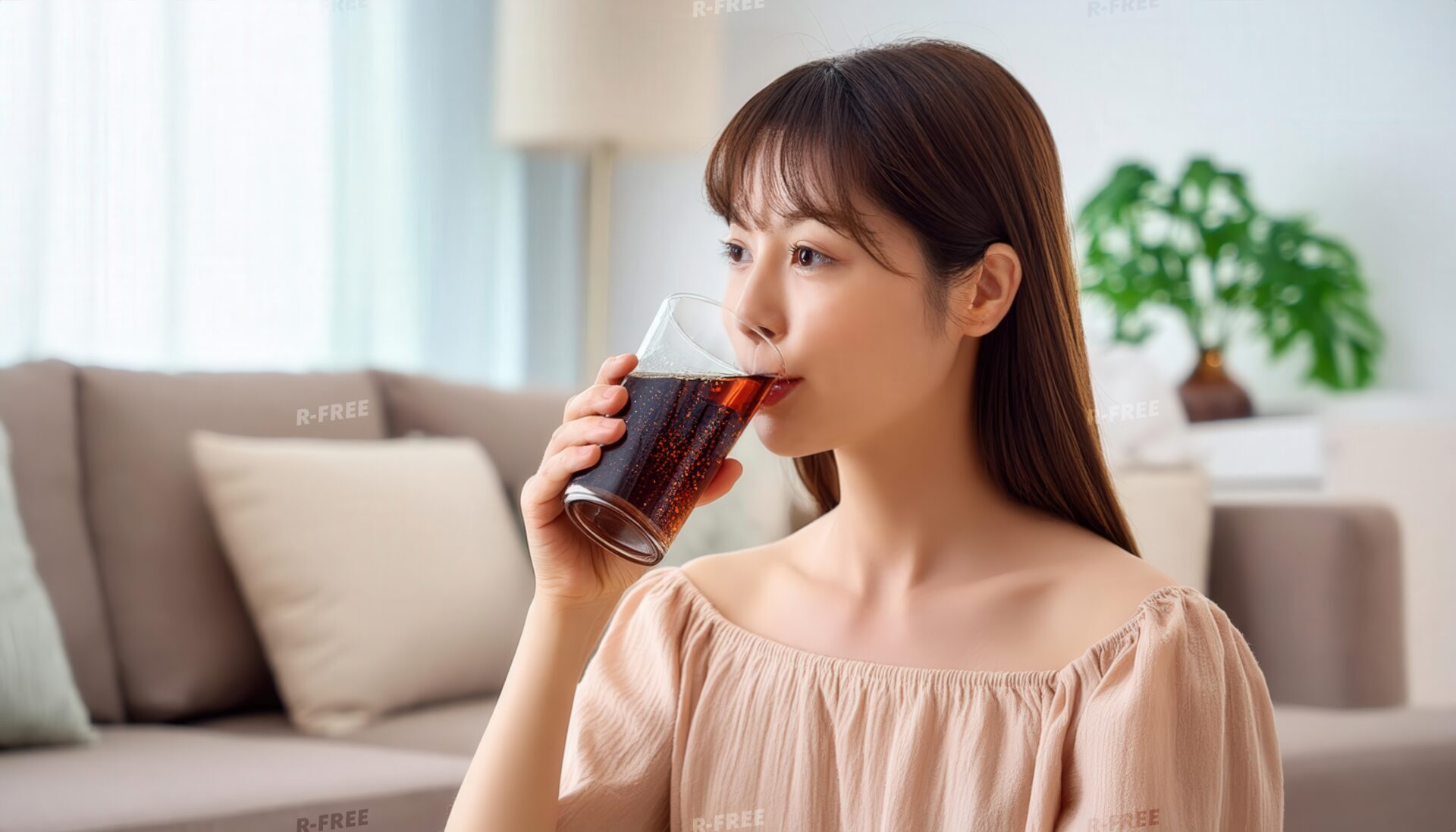 室内で黒い炭酸飲料を飲む長い茶髪の人