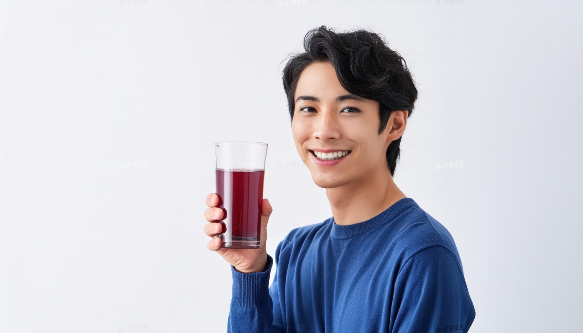 正面を向きグレープジュースを持つ青ニットの男性