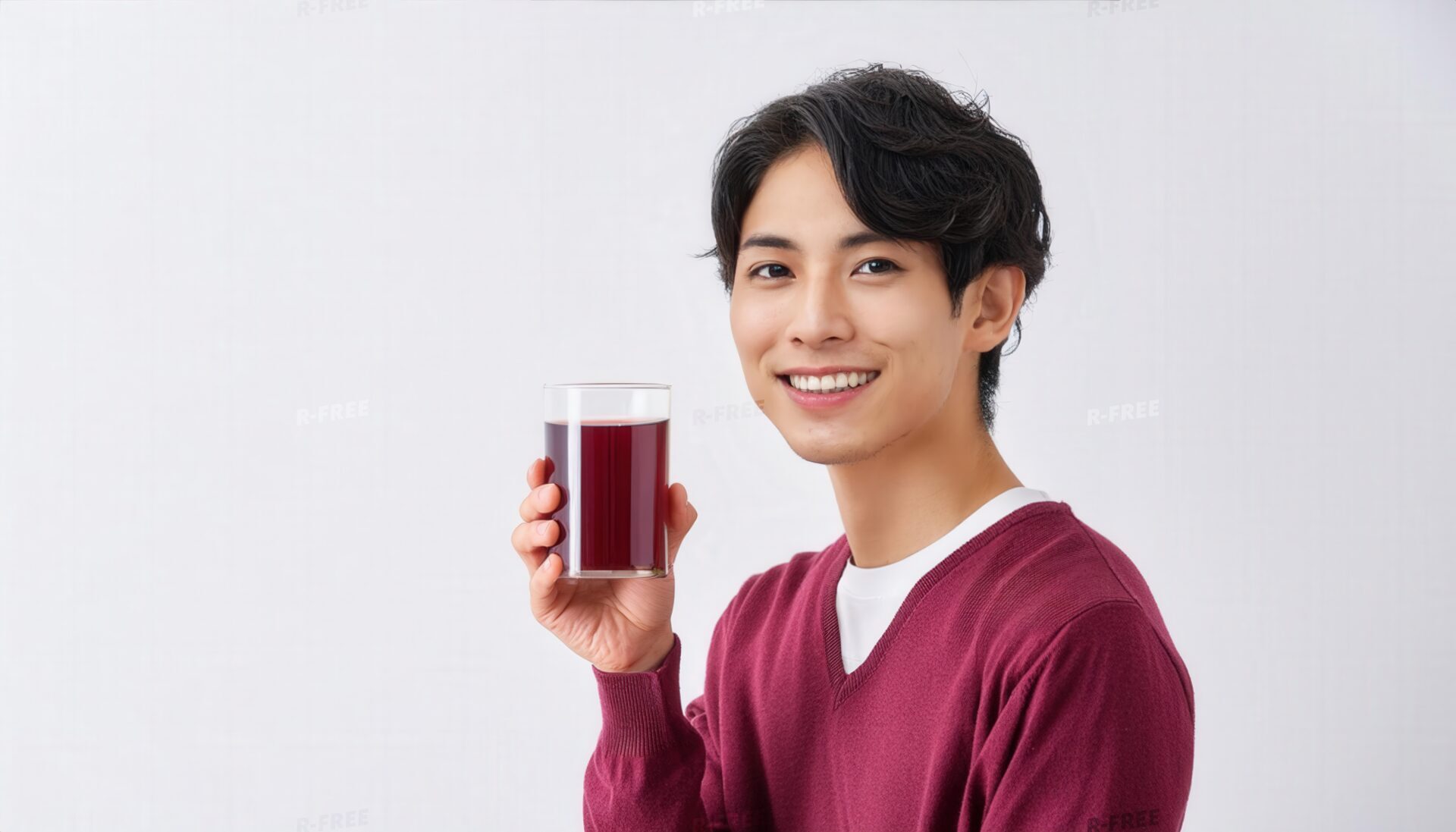 笑顔でグレープジュースを持つ赤紫セーターの男性
