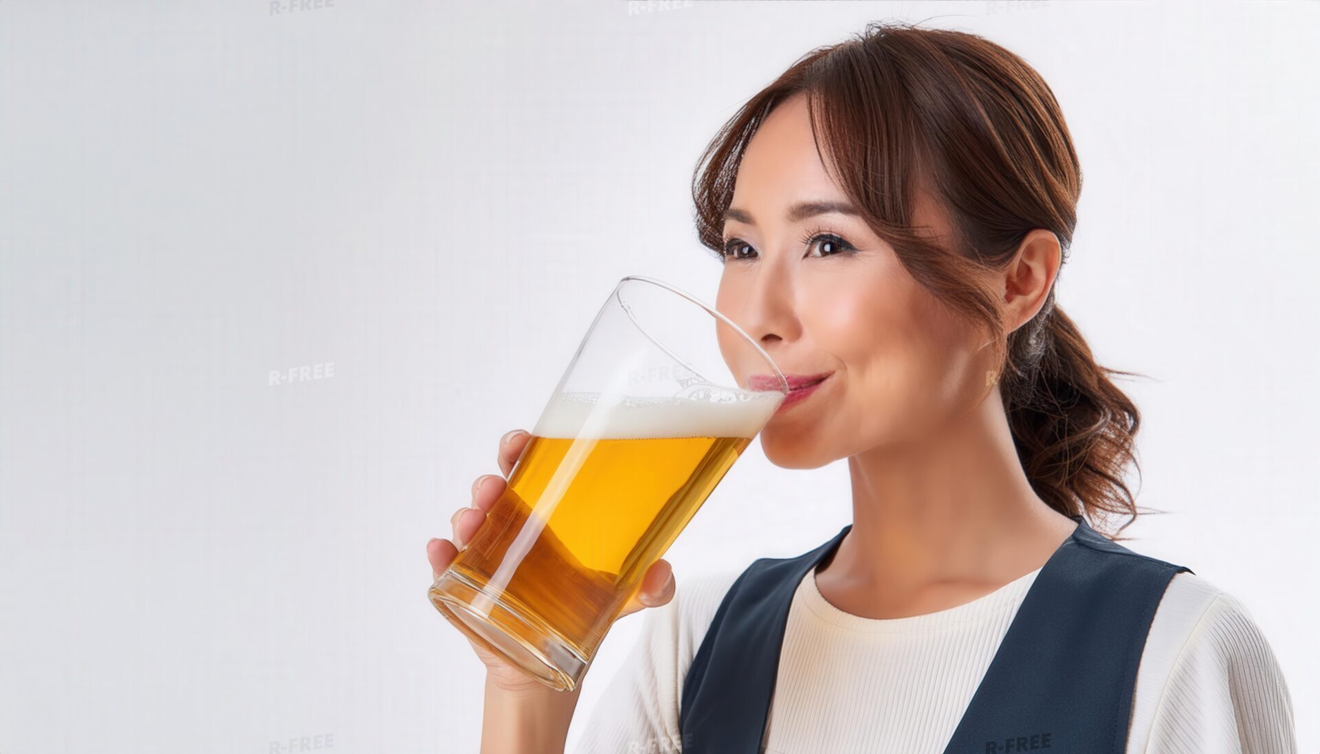 白いトップスと濃紺ベストでビールを飲む女性