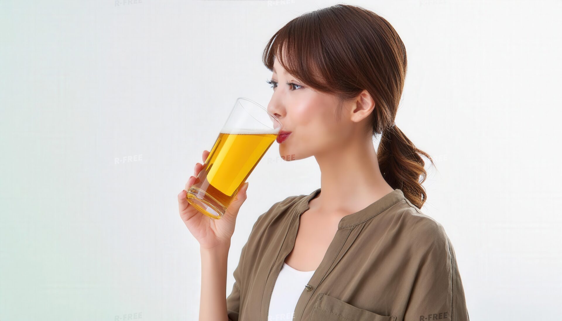 茶系シャツでビールを飲む髪をまとめた女性