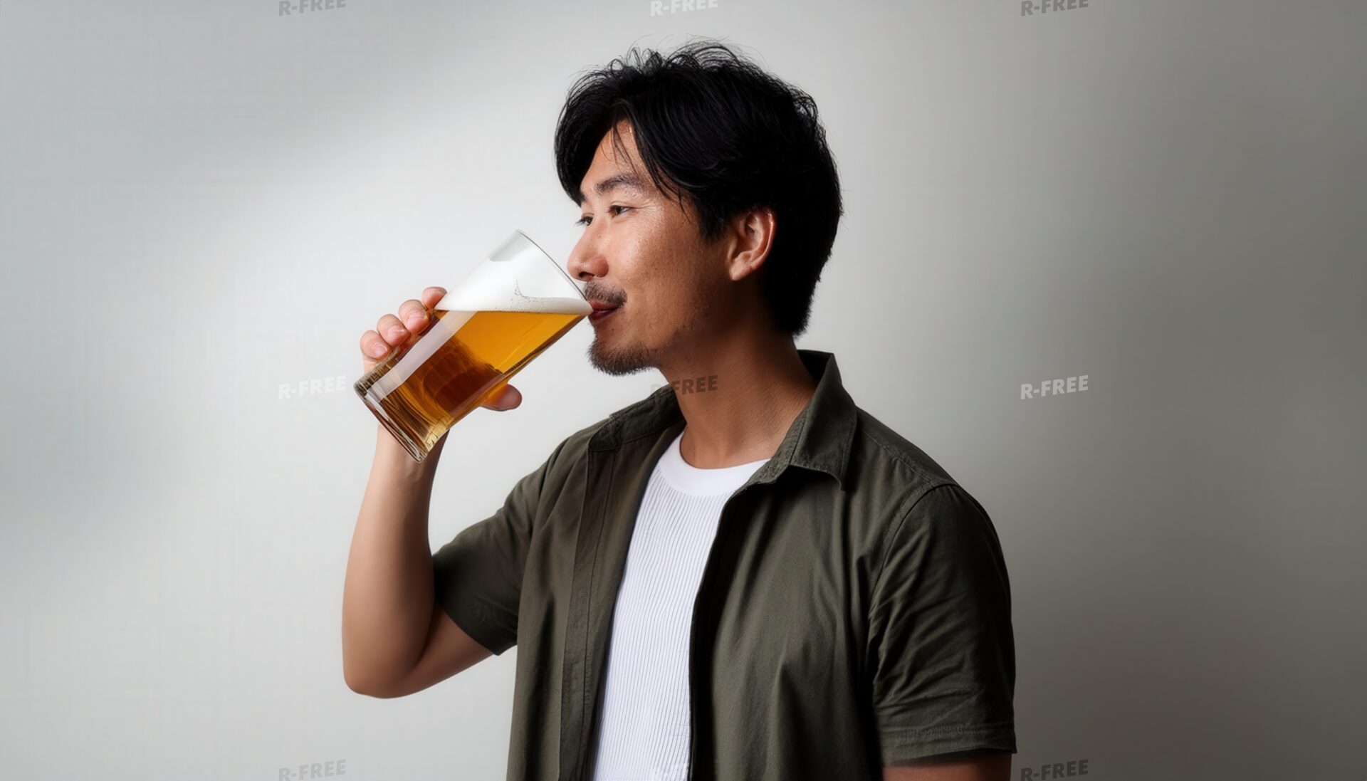 グレー背景でビールを飲む若い男性