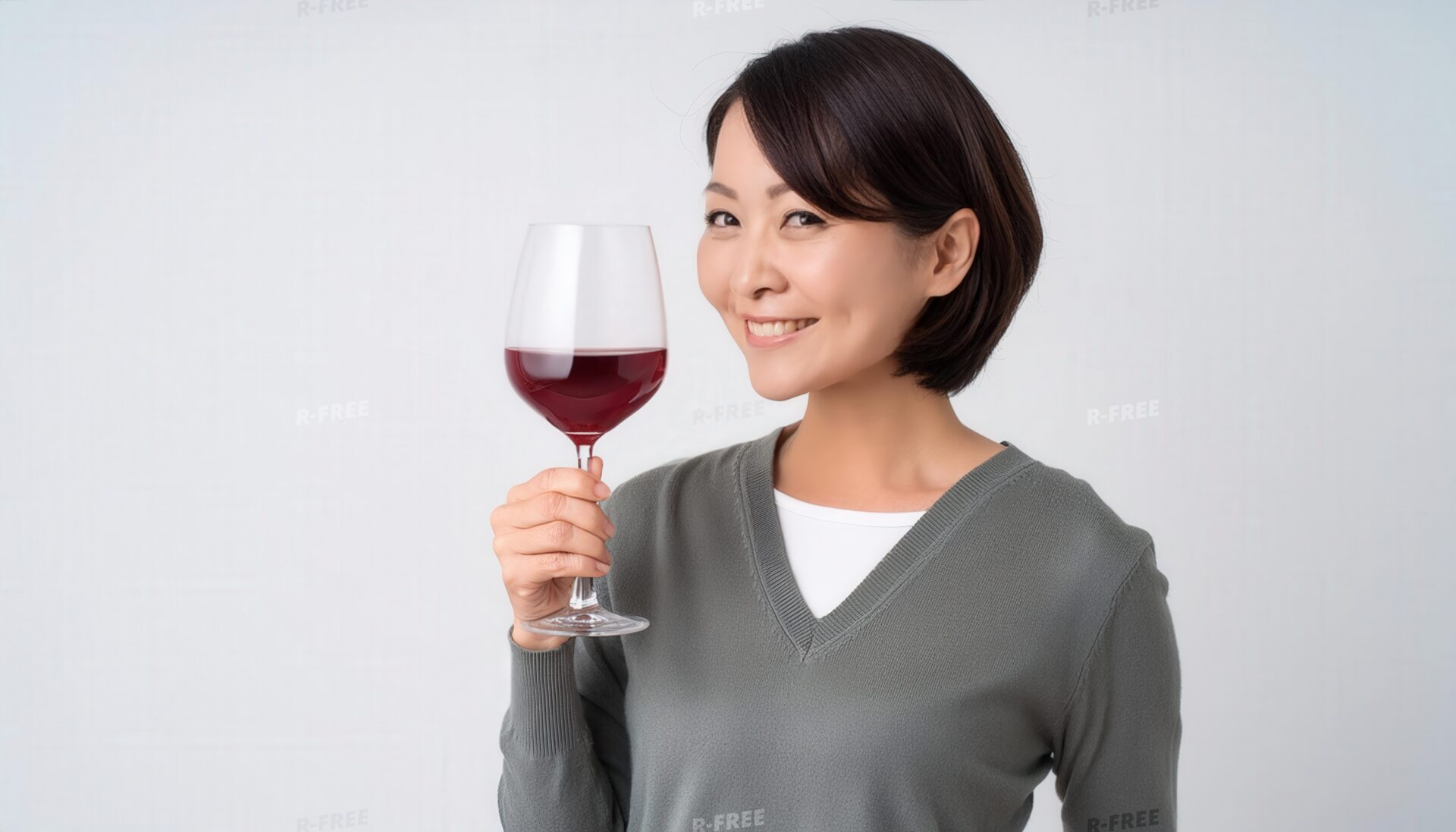 白背景でワイングラスを手に持つ笑顔の若い女性